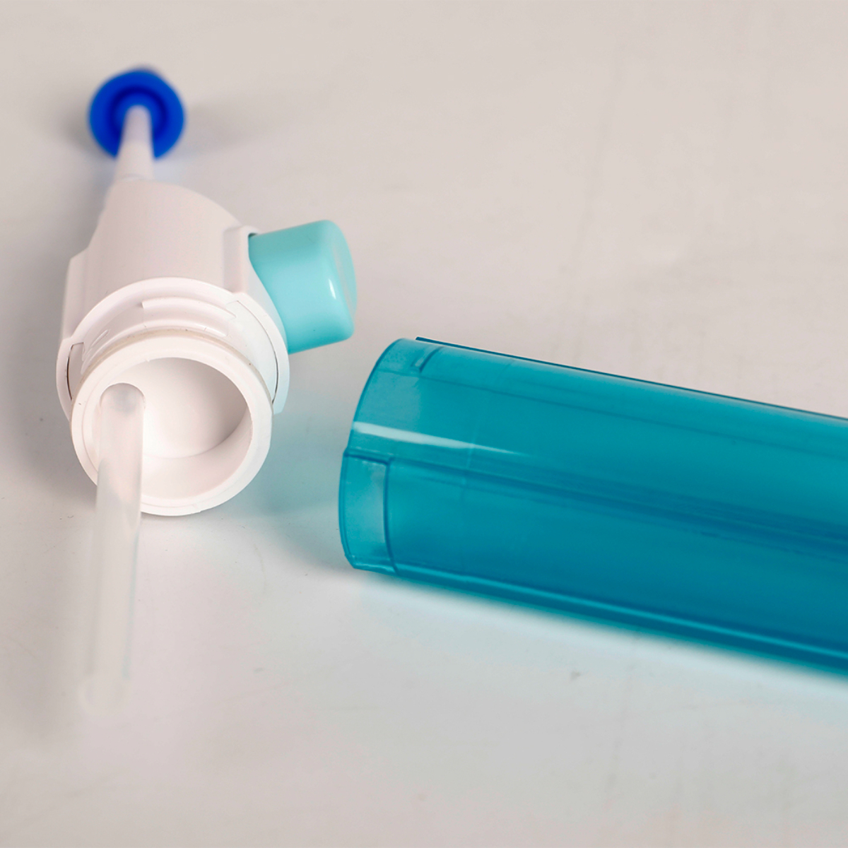 Cabezal de irrigador oral blanco con botón azul claro, con el depósito de agua separado.