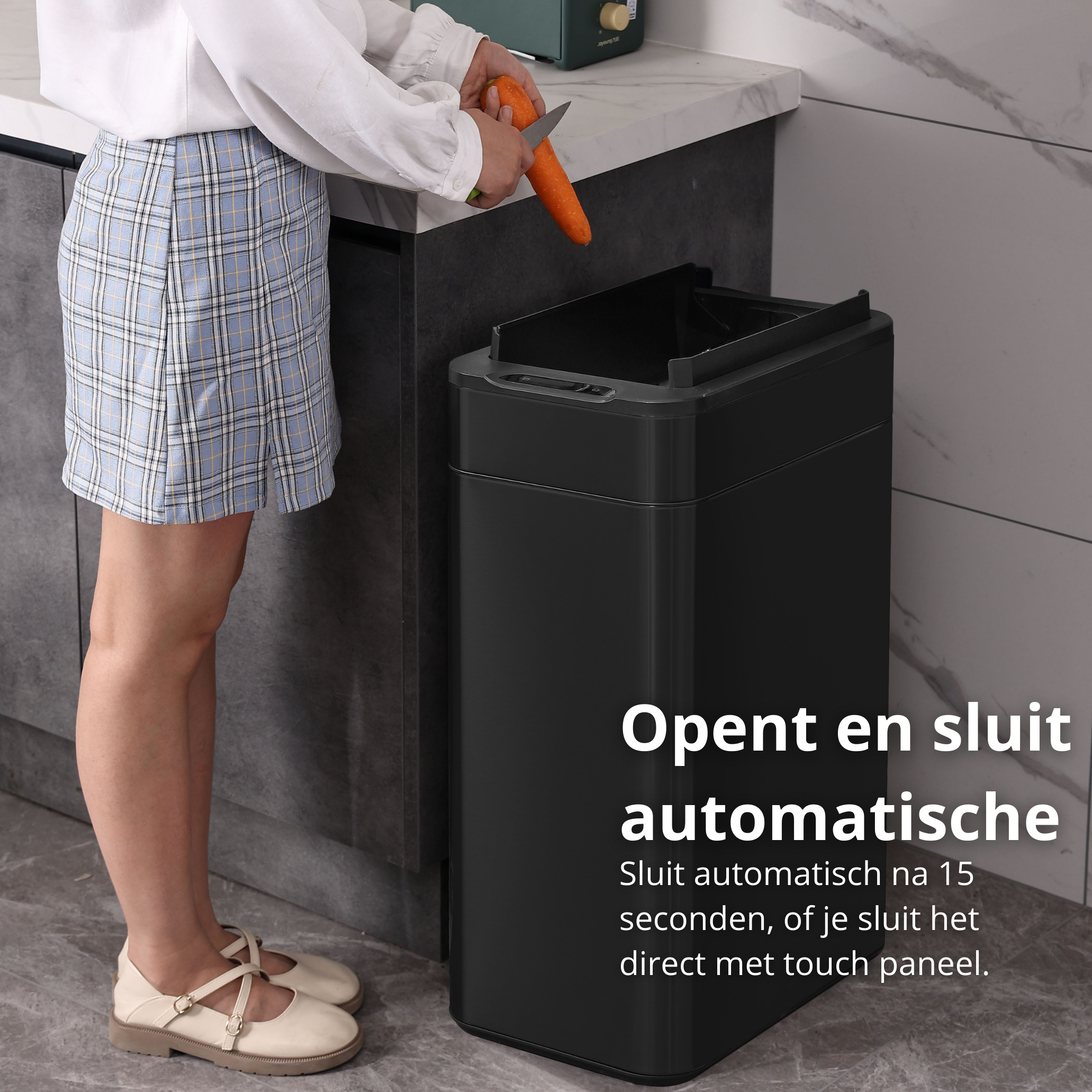 Woman cutting a carrot near a black trash can. The can has a lid open. Kitchen background.