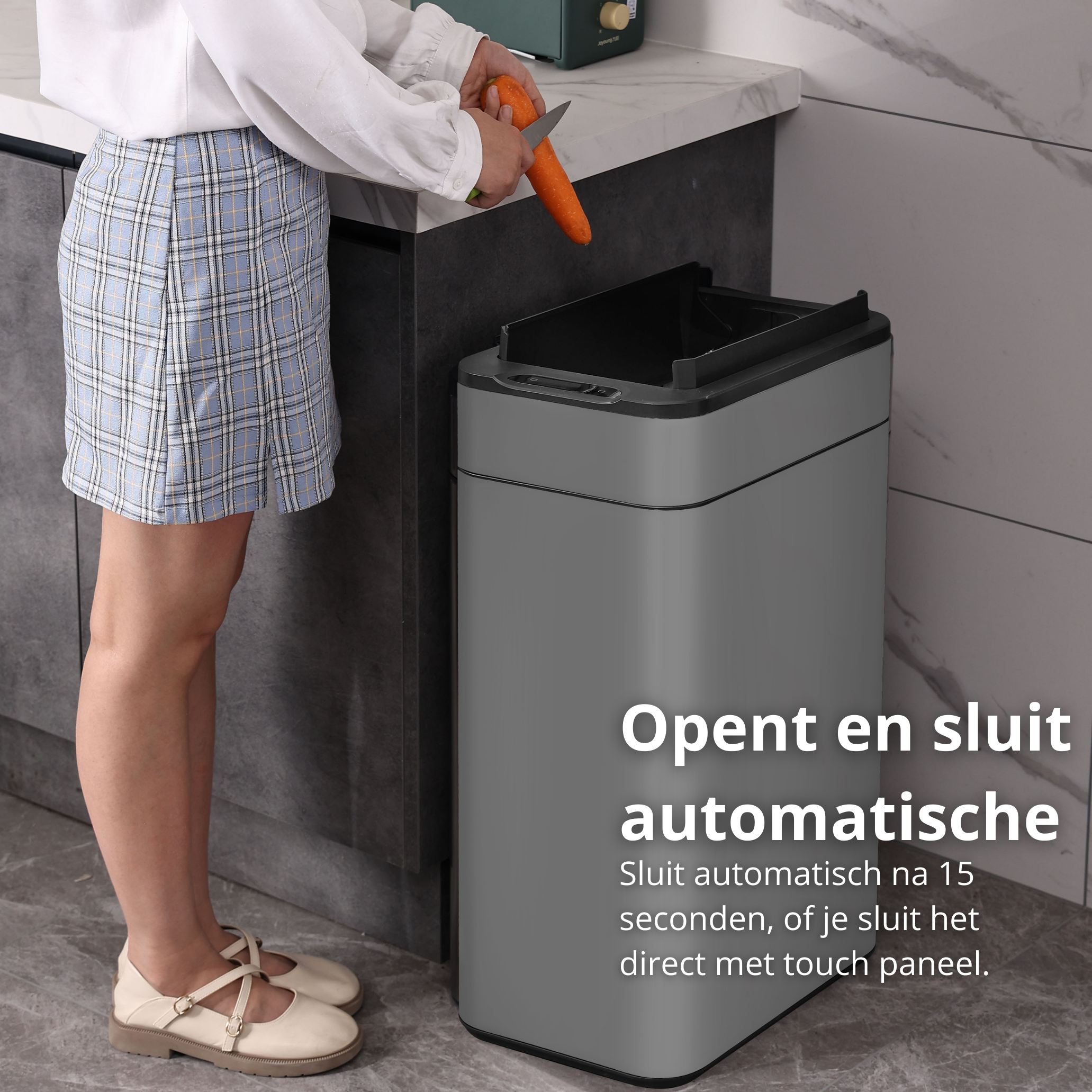 Person cutting carrot over a gray trash can in a kitchen.