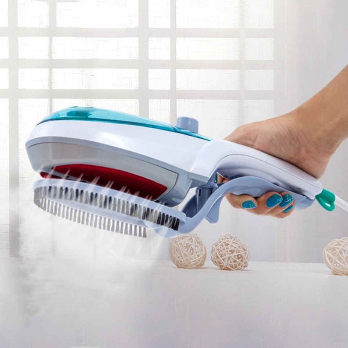 Mano sosteniendo plancha de vapor sobre superficie blanca con bolas decorativas. Fondo borroso.