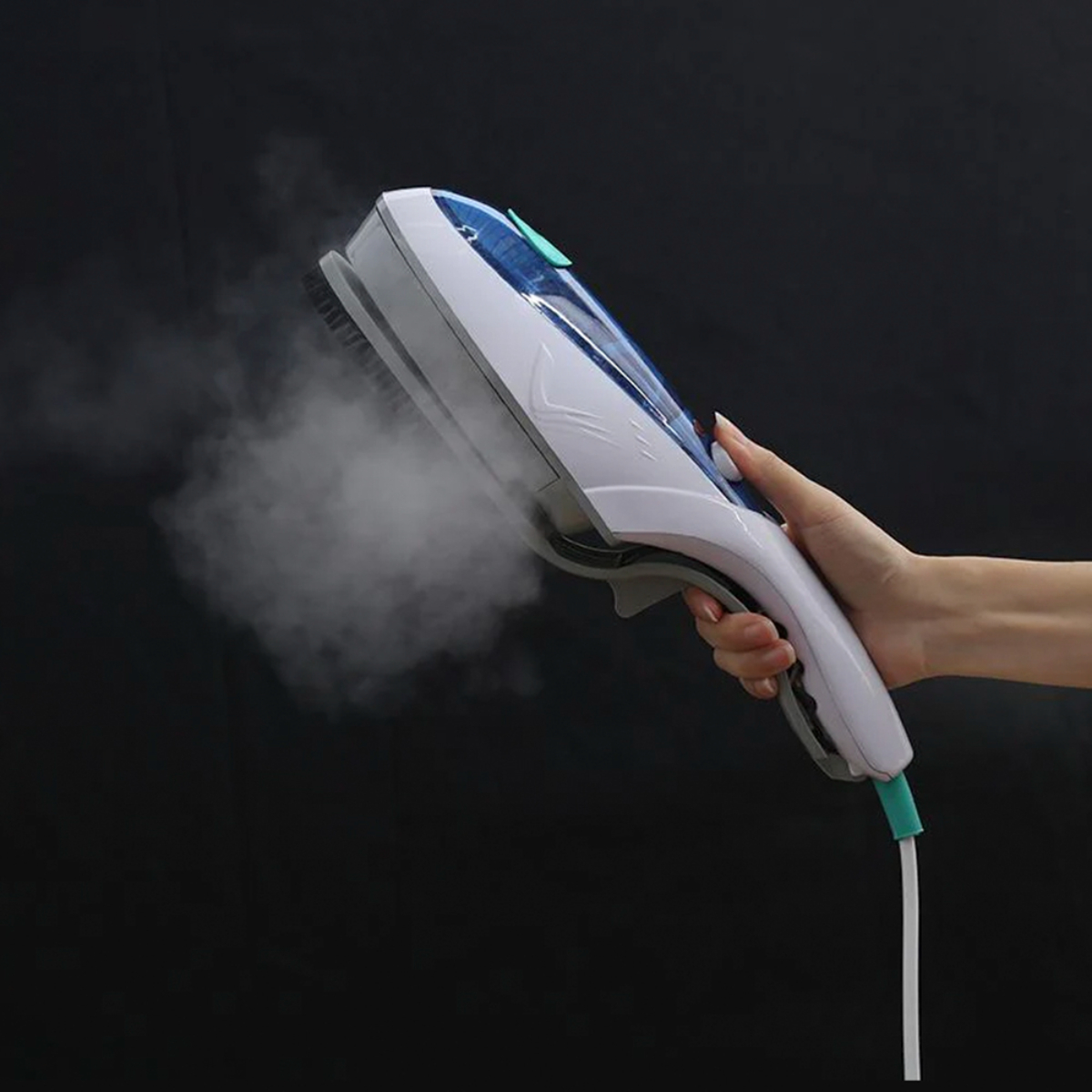 Mano sosteniendo vaporizador de ropa portátil blanco y azul. Vapor emanando, contra fondo negro.