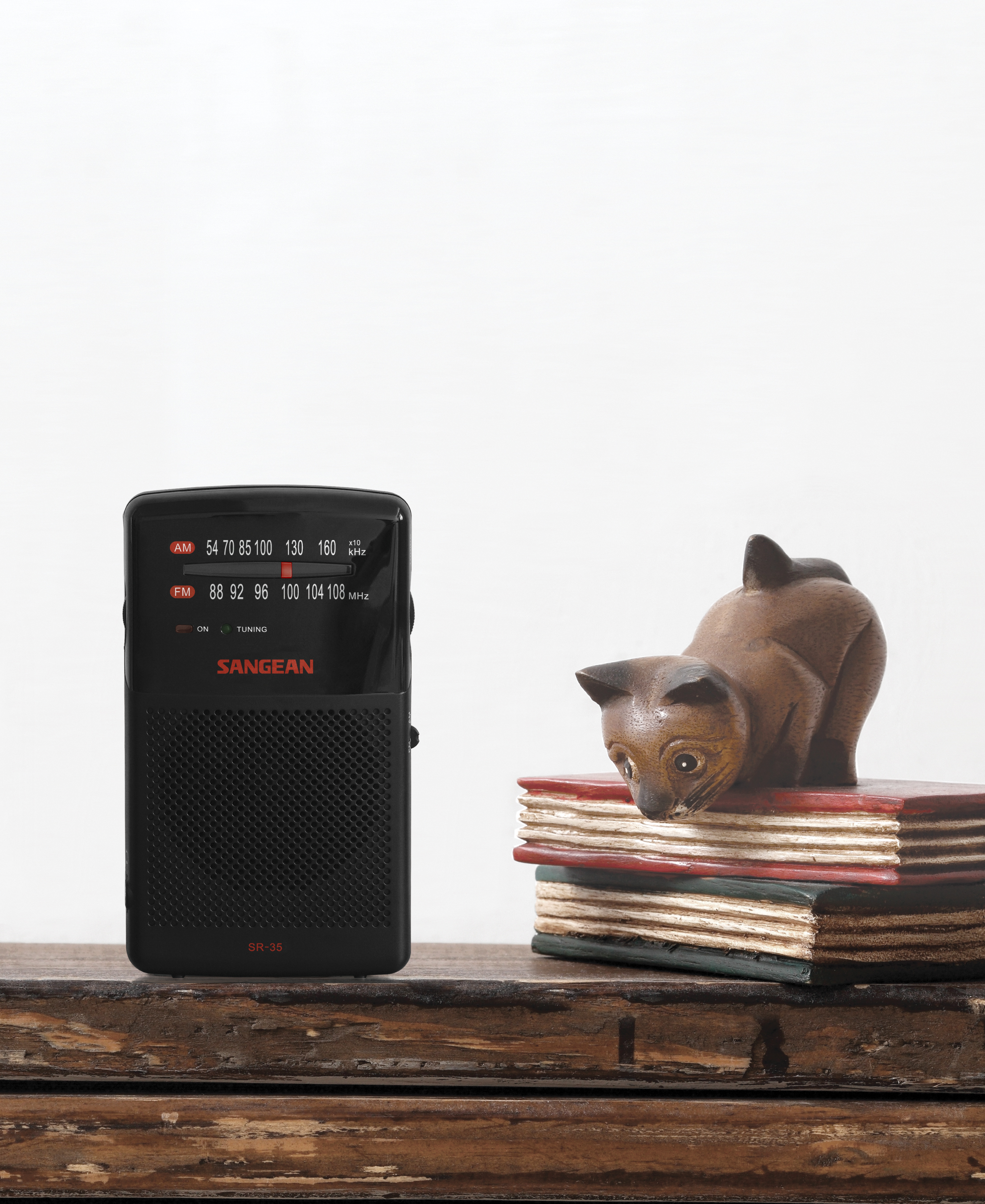 Black radio and cat figurine on a wooden surface.
