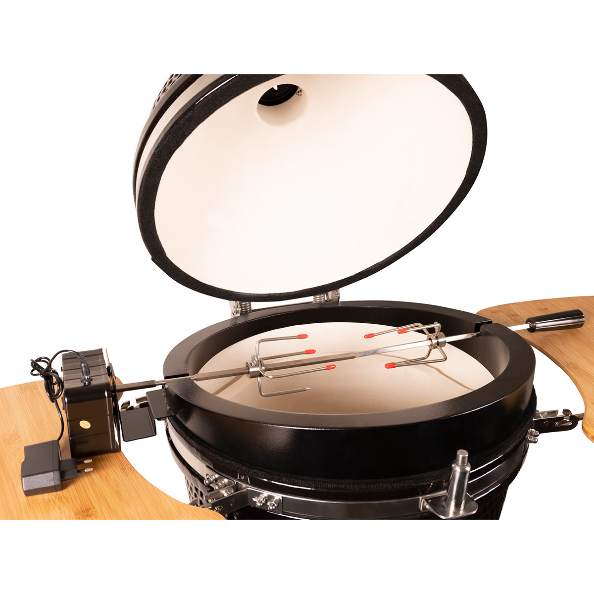Kamado grill met open deksel, rotisserie binnenin, op een houten oppervlak.