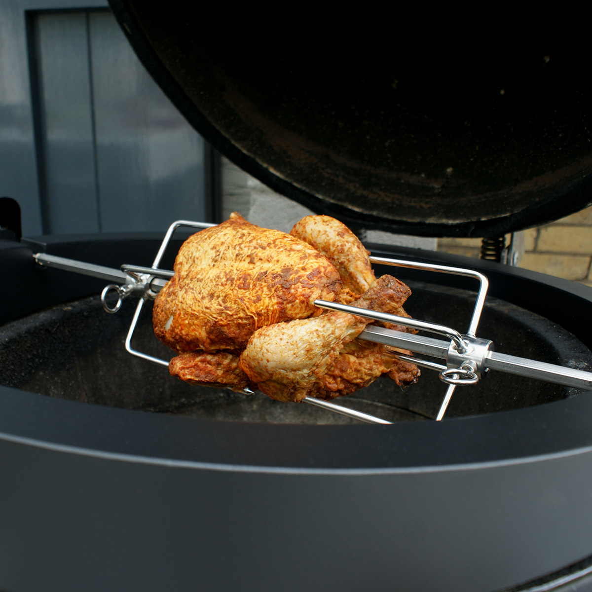 Rotisserie kip die kookt in een zwarte grill met het deksel open.