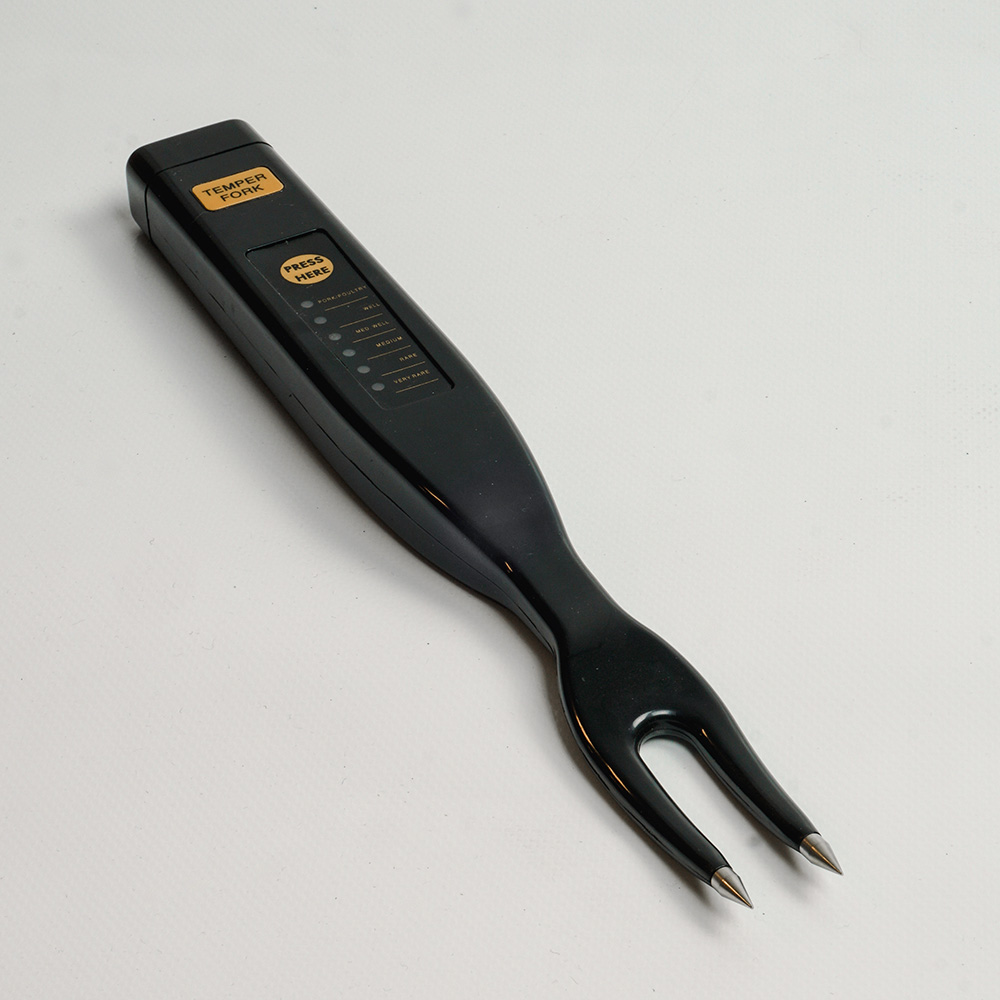 Black meat thermometer with two prongs, with a series of temperature indicators.