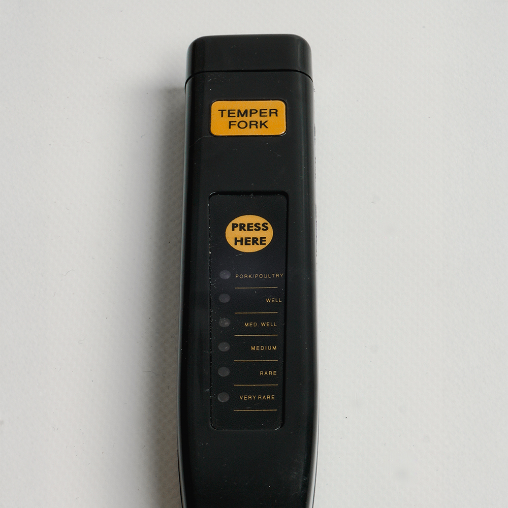 Black meat thermometer, labeled, with a scale for cooking levels.