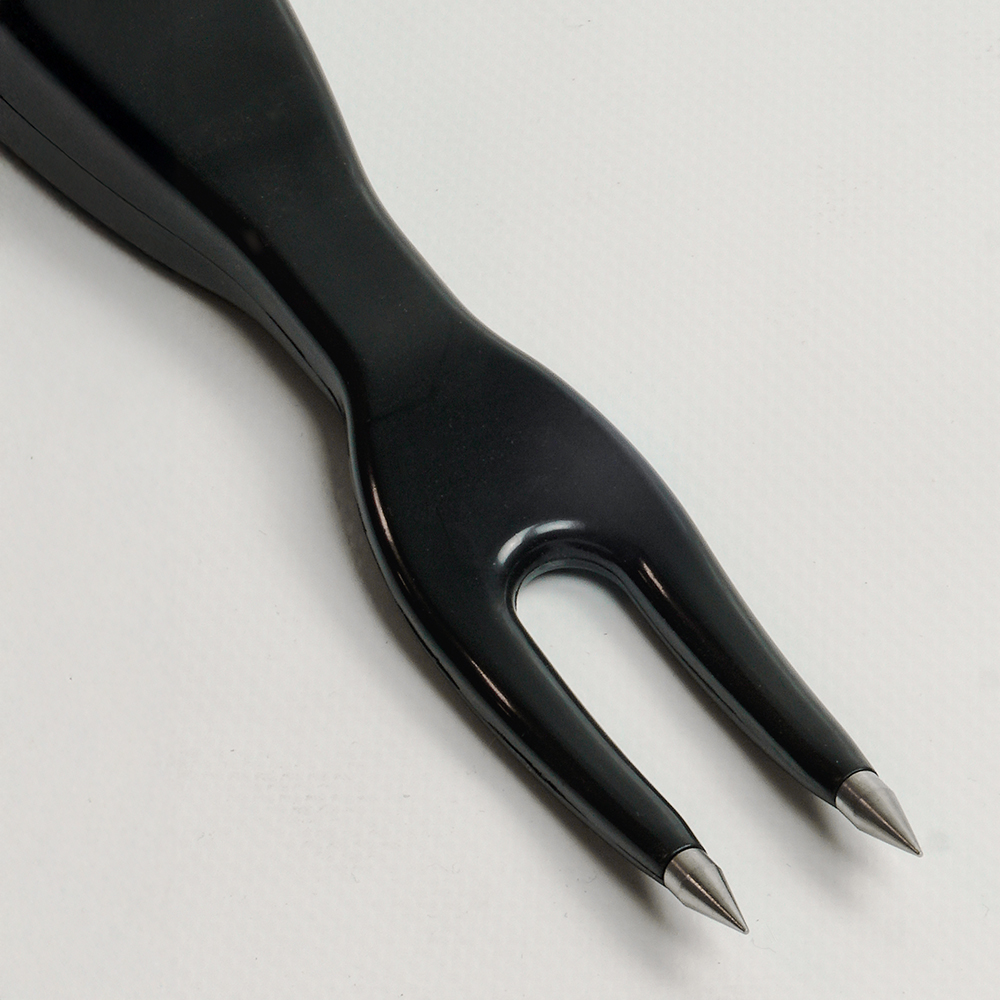 Close up of black meat thermometer prongs with a white background.
