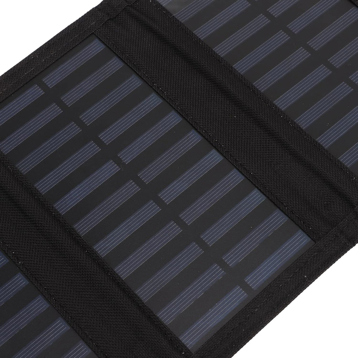 Primer plano de un panel solar negro con múltiples celdas rectangulares azul oscuro y rayas negras. Fondo negro.