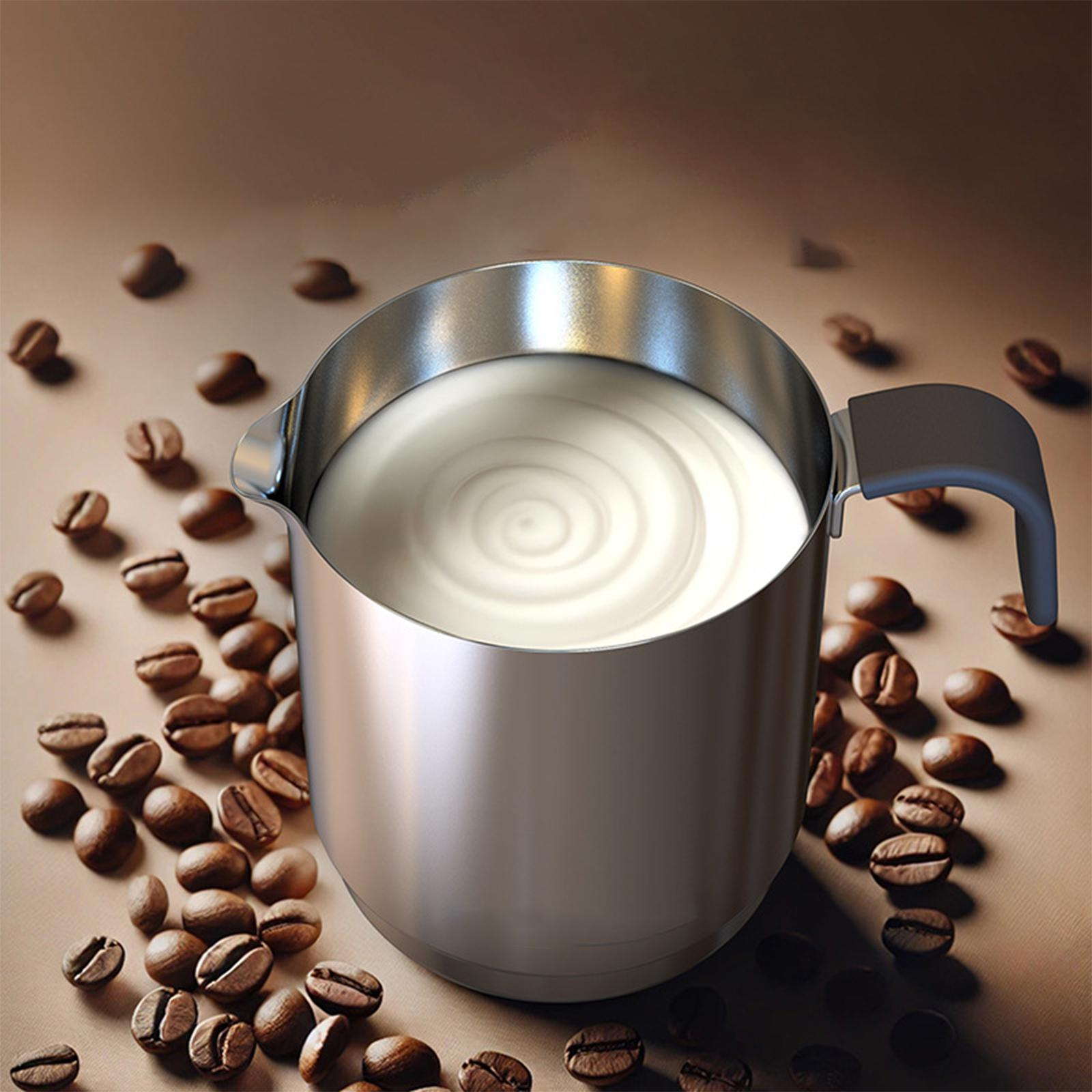Edelstahlkrug mit Milch und Kaffeebohnen auf brauner Oberfläche.
