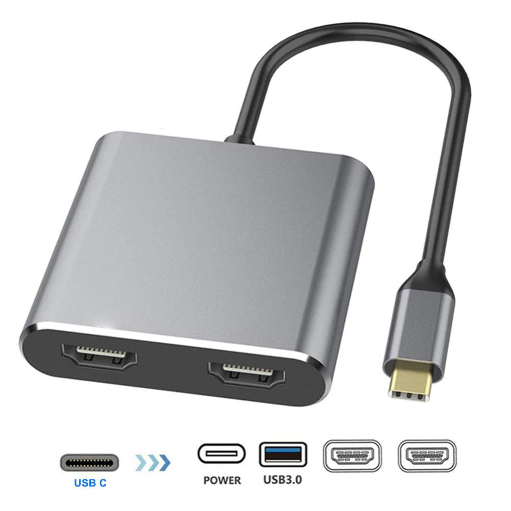 Ein silberner USB-C-Hub mit HDMI- und USB 3.0-Anschlüssen und verschiedenen Konnektorsymbolen.
