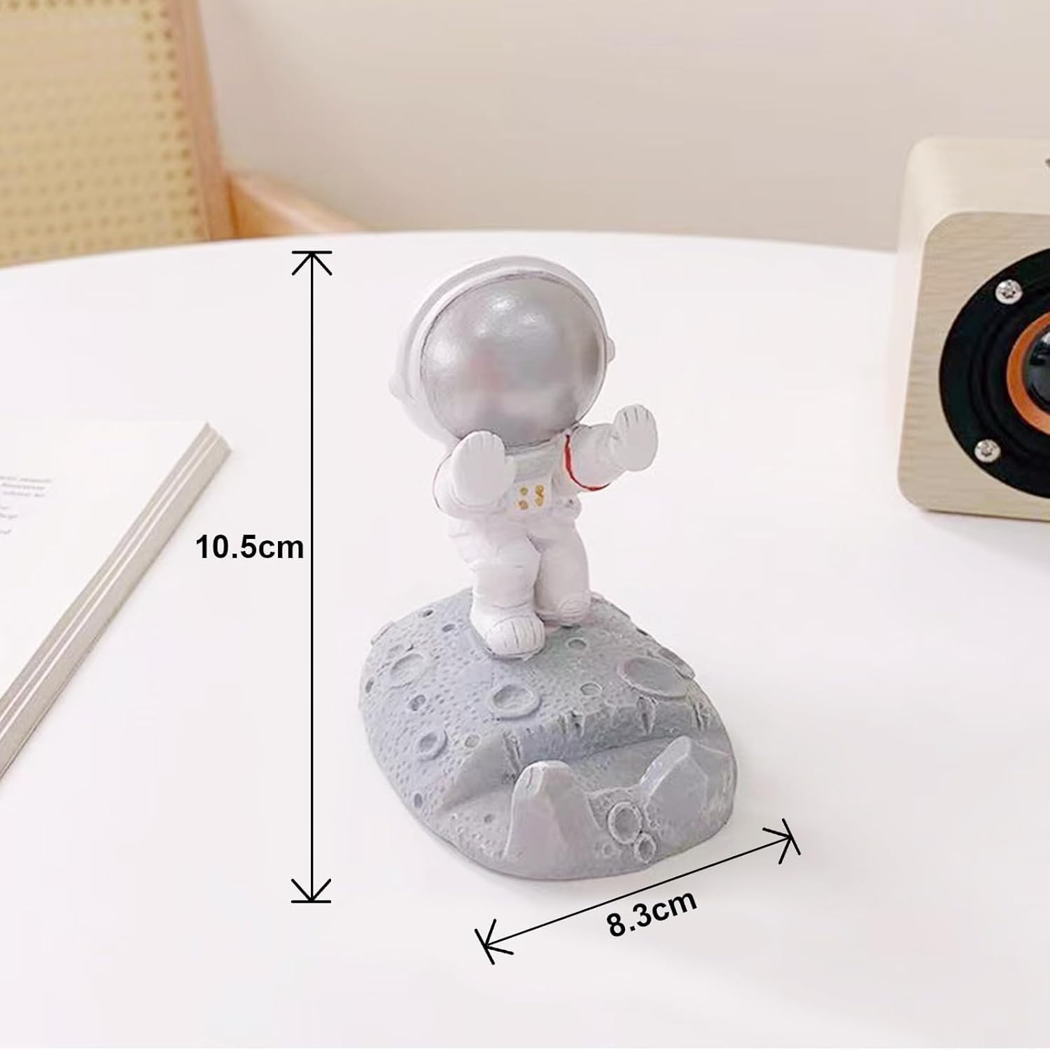 Astronauten-Telefonständer auf einem Tisch. Astronautenfigur ist weiß. Maße: 10,5 cm Höhe, 8,3 cm Breite.