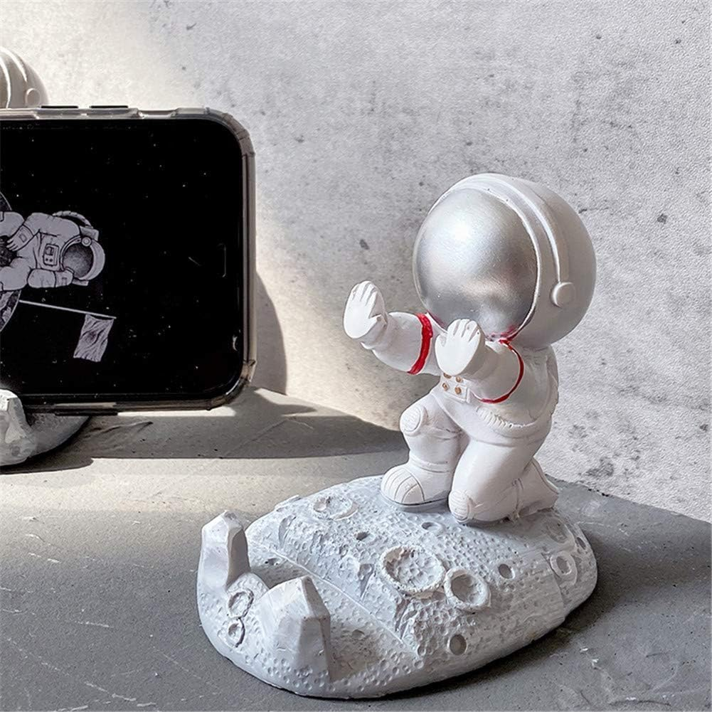 Eine Astronautenfigur auf einer mondähnlichen Basis mit einem Telefon, das eine Weltraumszene zeigt. Der Astronaut ist weiß.