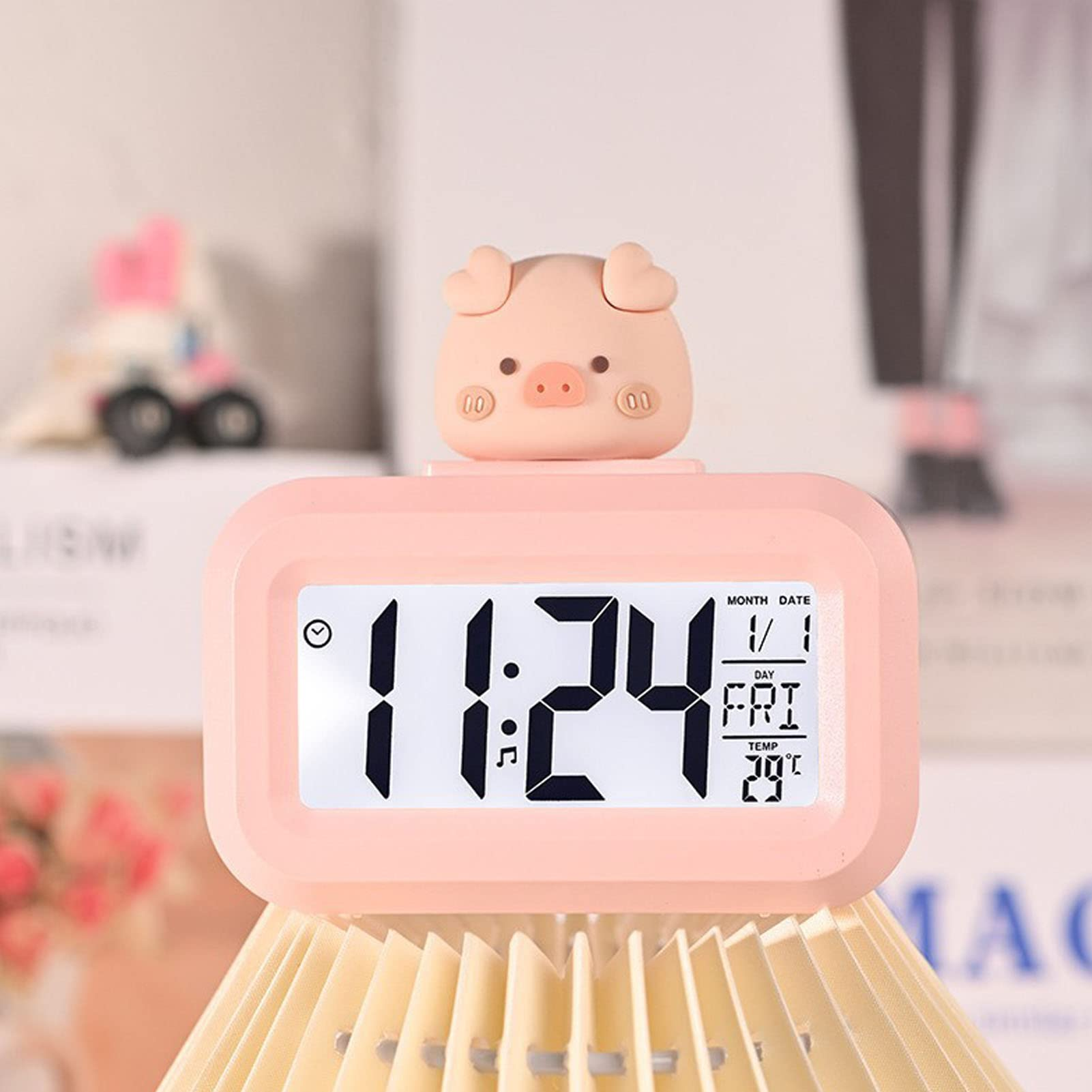 Rosa Förmiger Digitalwecker mit 11:24. Datum, Tag und Temperatur sind sichtbar.
