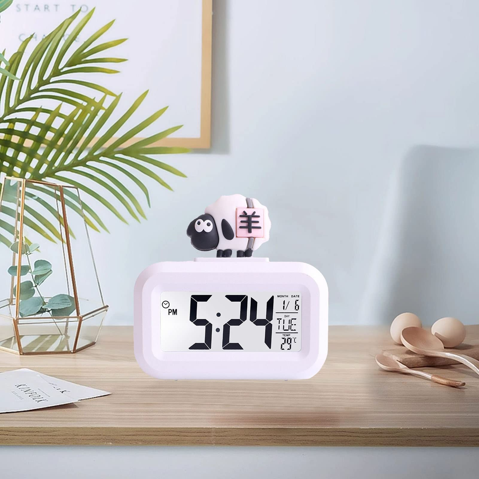 Eine rosa schafartige Uhr auf einem Schreibtisch, die Uhr zeigt 5:24 und das Datum ist der 1/6.
