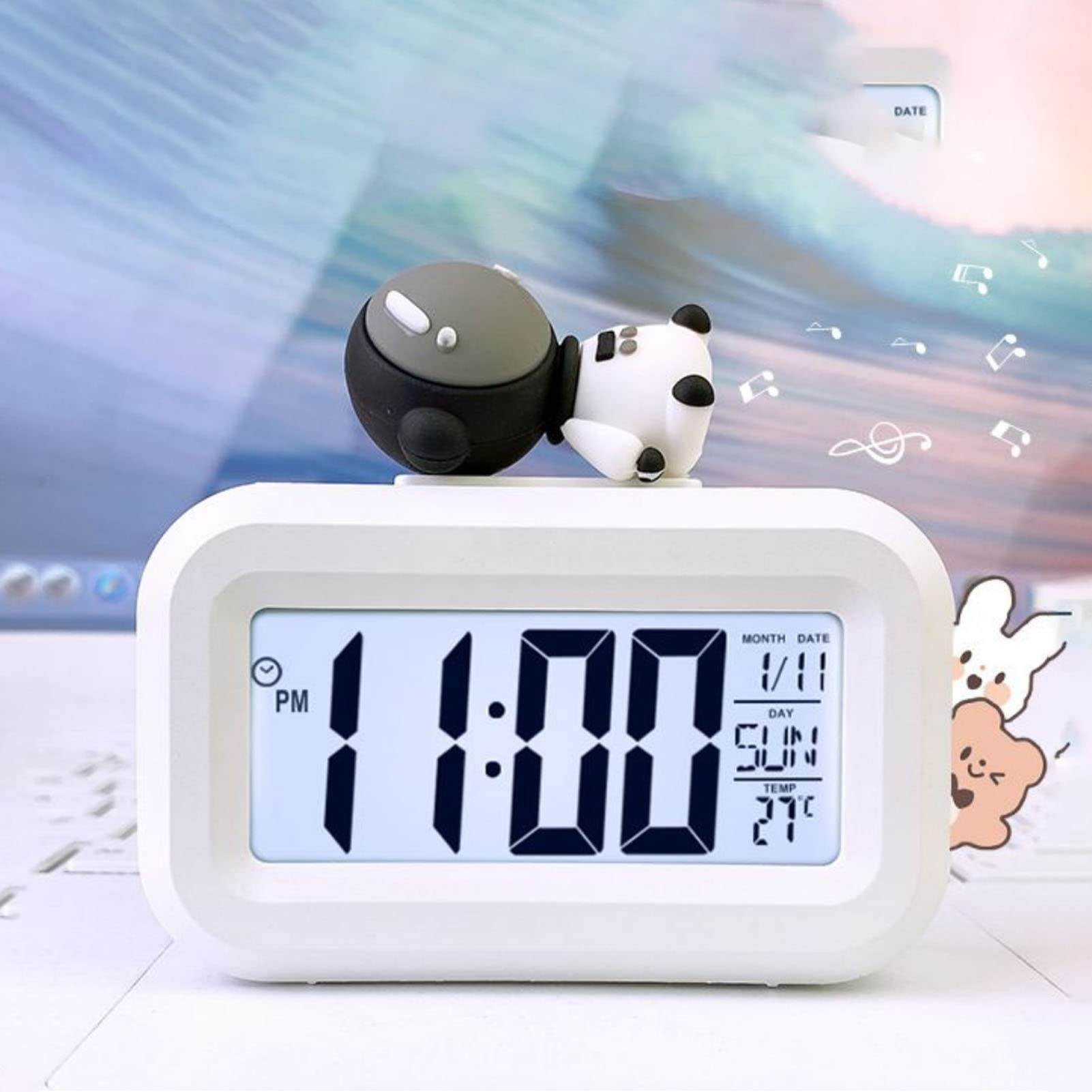 Eine weiße Digitaluhr mit einer Panda-Figur obenauf. Die Uhr zeigt 11:00 Uhr, Datum, Tag und Temperatur an.