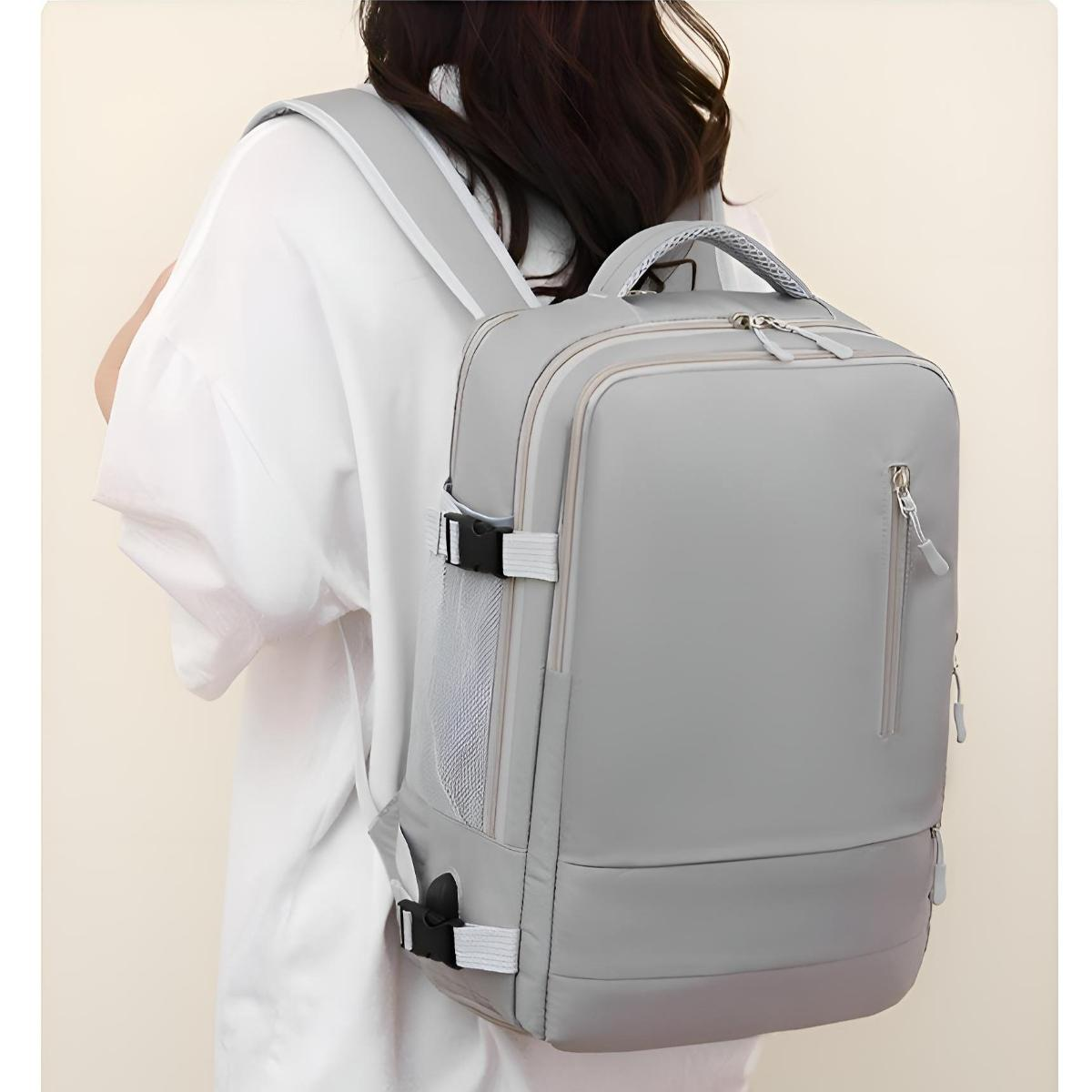 Eine Frau trägt einen grauen Rucksack. Der Rucksack hat mehrere Fächer.