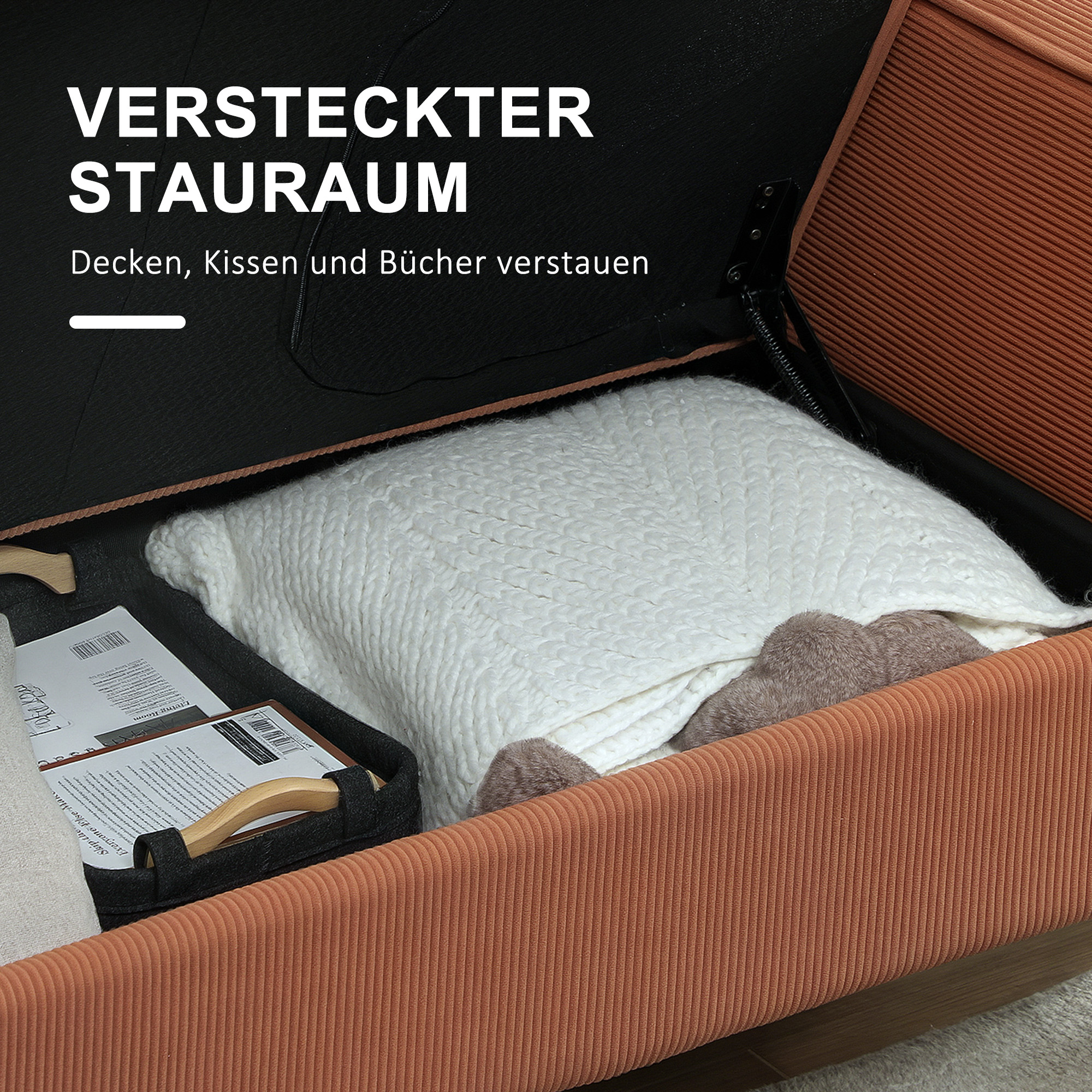 Offenes Sofa mit verstecktem Stauraum. Eine weiße Decke, ein schwarzer Korb mit Büchern und Kissen sind sichtbar.