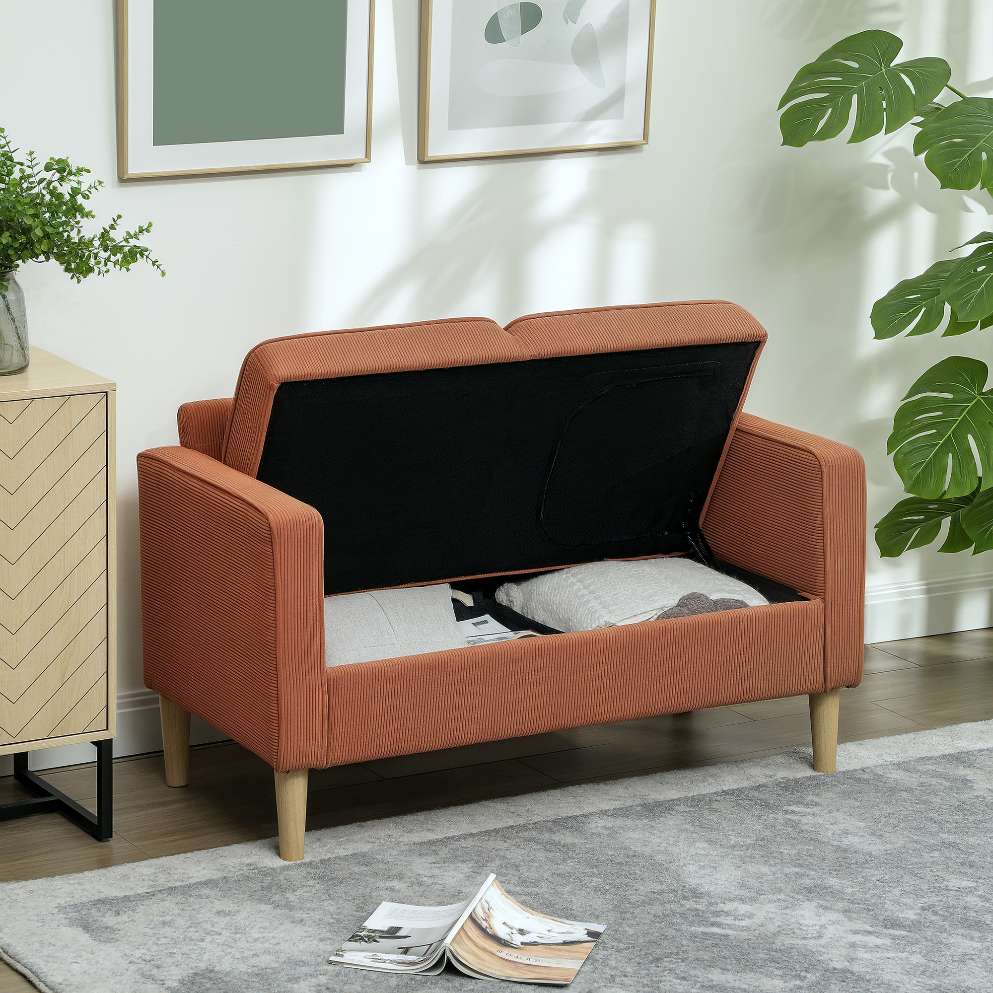 Ein orangefarbenes Sofa mit offenem Stauraum. Ein Buch befindet sich im Vordergrund.