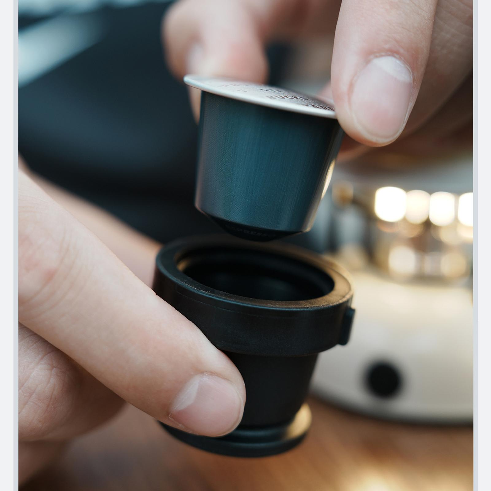 Hände halten Kaffeekapsel und Kaffeemaschinenteil, bereiten das Brühen vor.