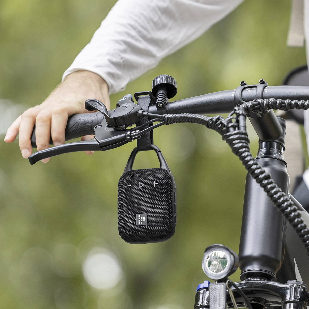 Person fährt Fahrrad mit einem schwarzen Lautsprecher am Lenker befestigt.