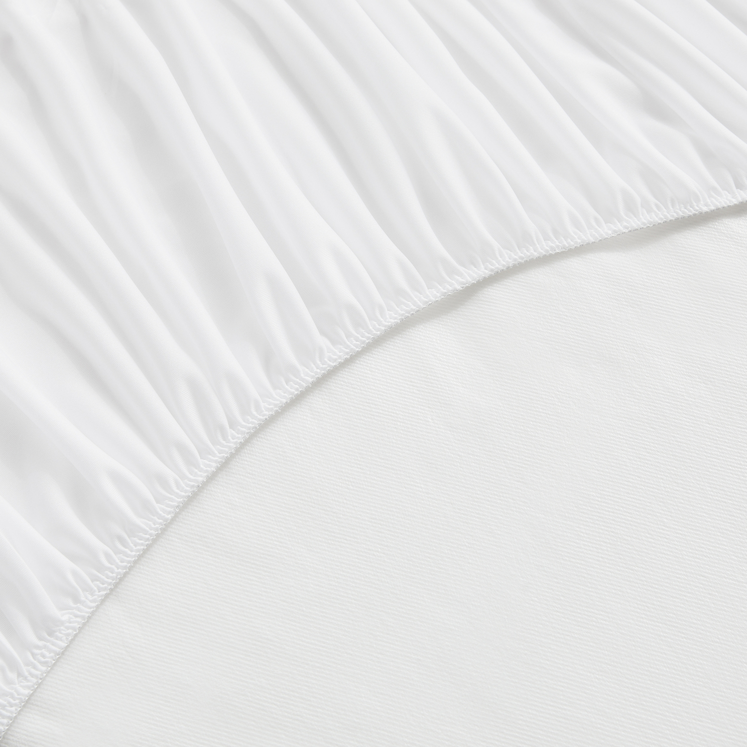Primer plano de ropa de cama blanca, mostrando el borde de una sábana ajustable.