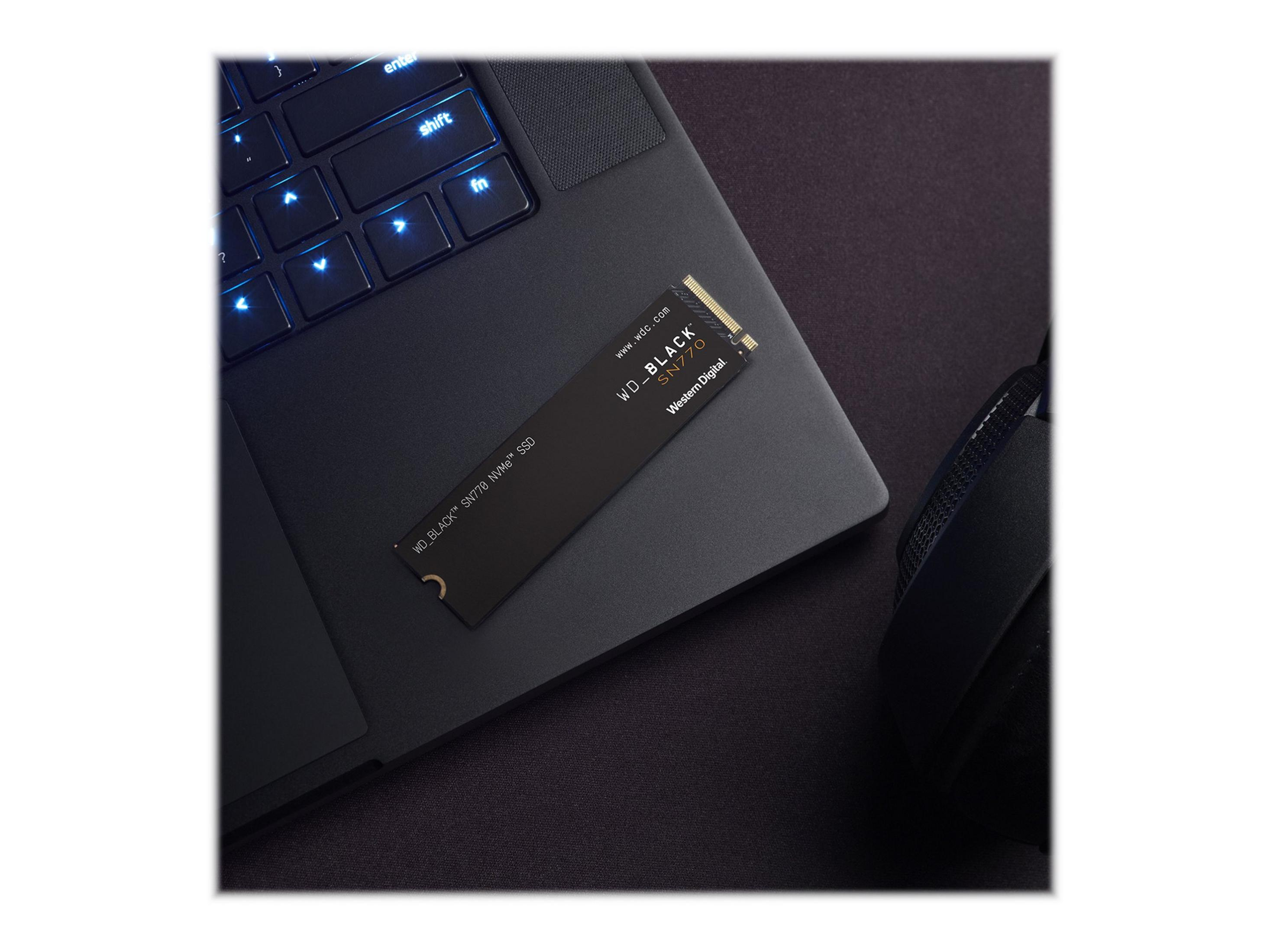 SSD WD_BLACK SN770 su un laptop. SSD nero su un laptop nero. Cuffie sullo sfondo.
