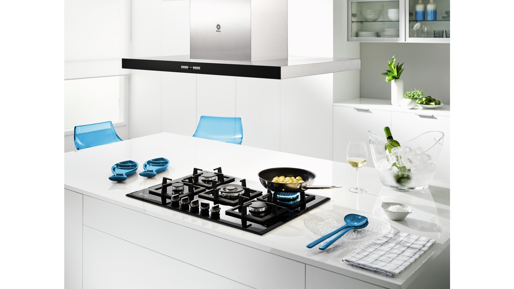 Nowoczesna kuchnia z płytą grzewczą, wyspą i okapem ze stali nierdzewnej. Niebieskie krzesła.