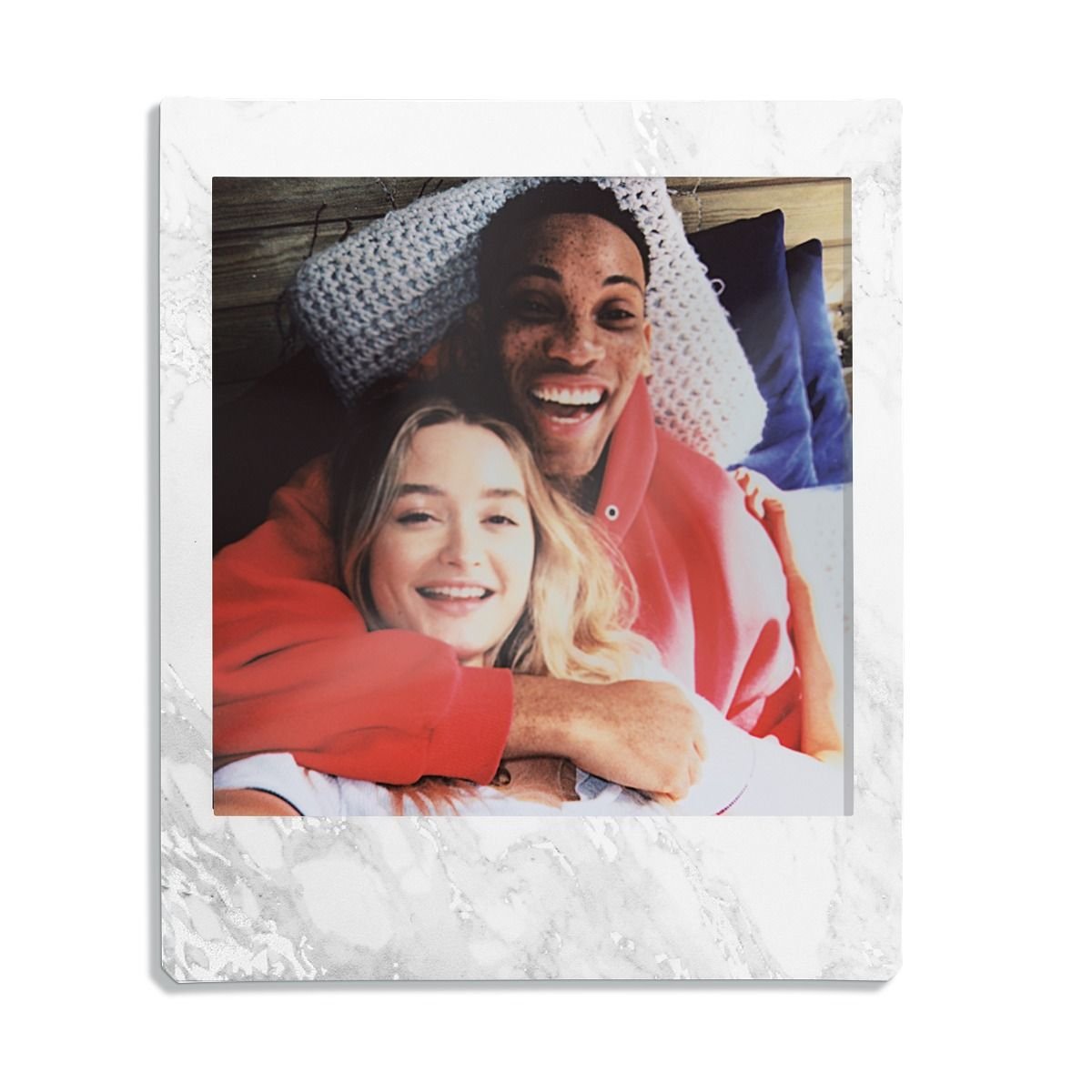 Zdjęcie polaroid uśmiechniętej pary obejmującej się, w marmurowej ramie.