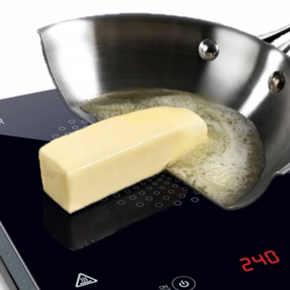 Patelnia na płycie grzewczej z roztopionym masłem i kostką masła.