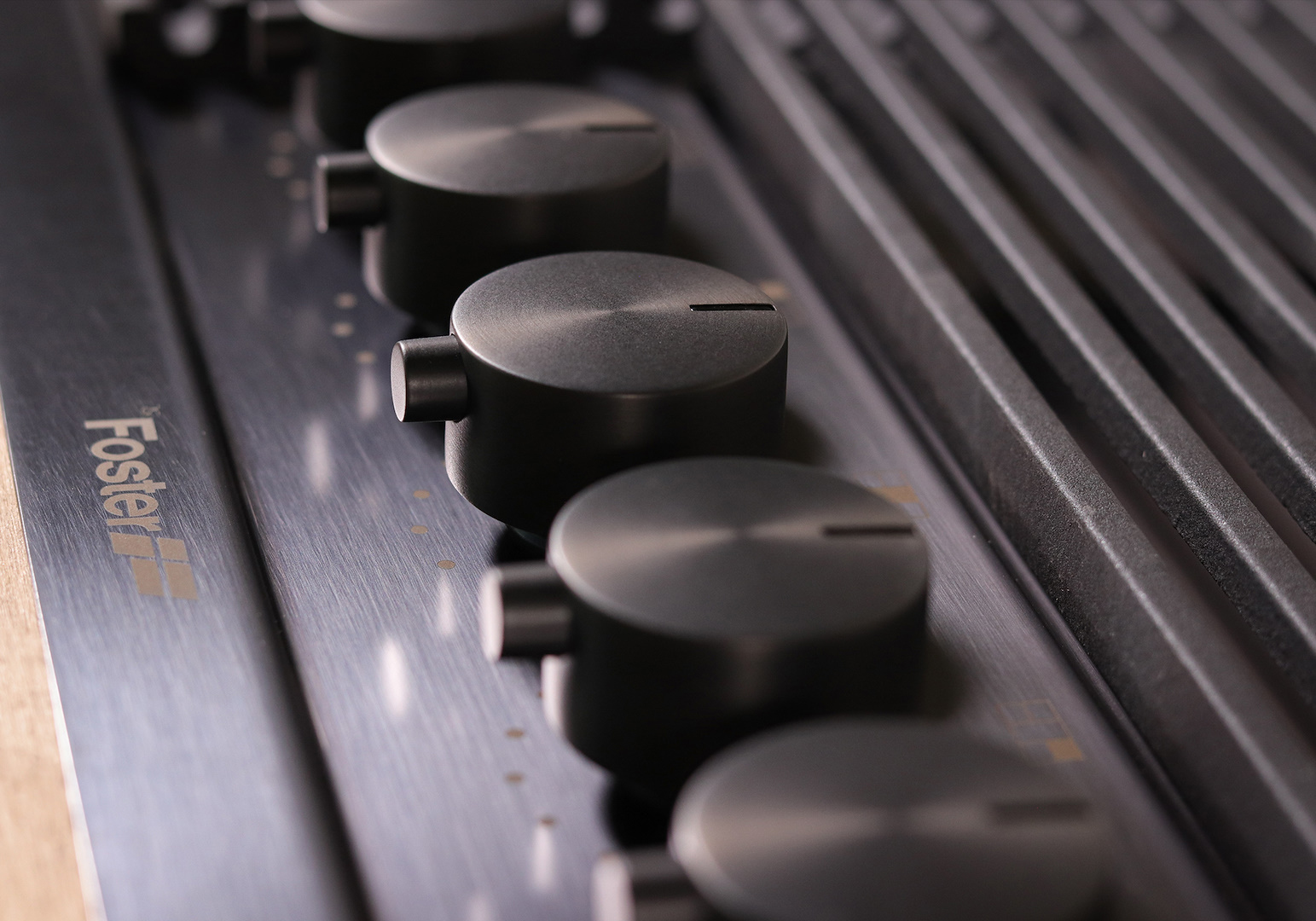 Primo piano di piano cottura a gas con manopole nere e superficie metallica. Marchio Foster visibile.
