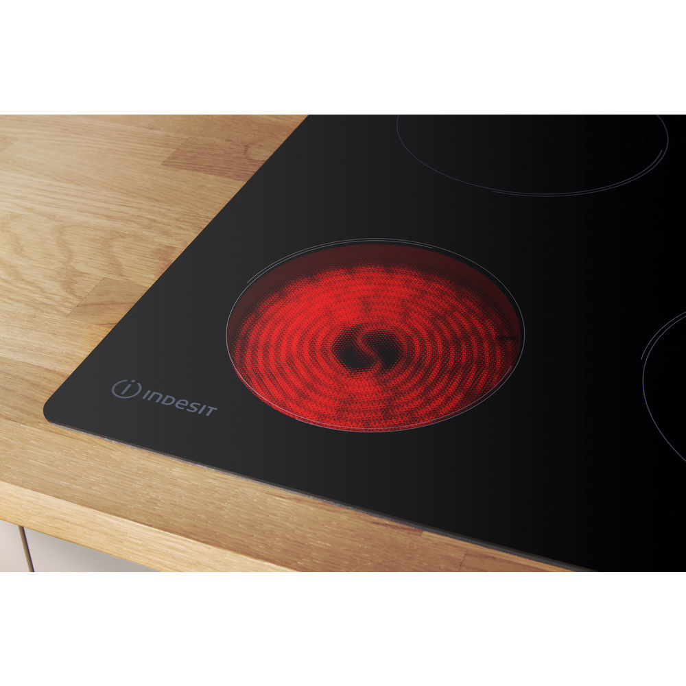 Primer plano de una placa de inducción con un círculo de quemador rojo brillante. Superficie negra.
