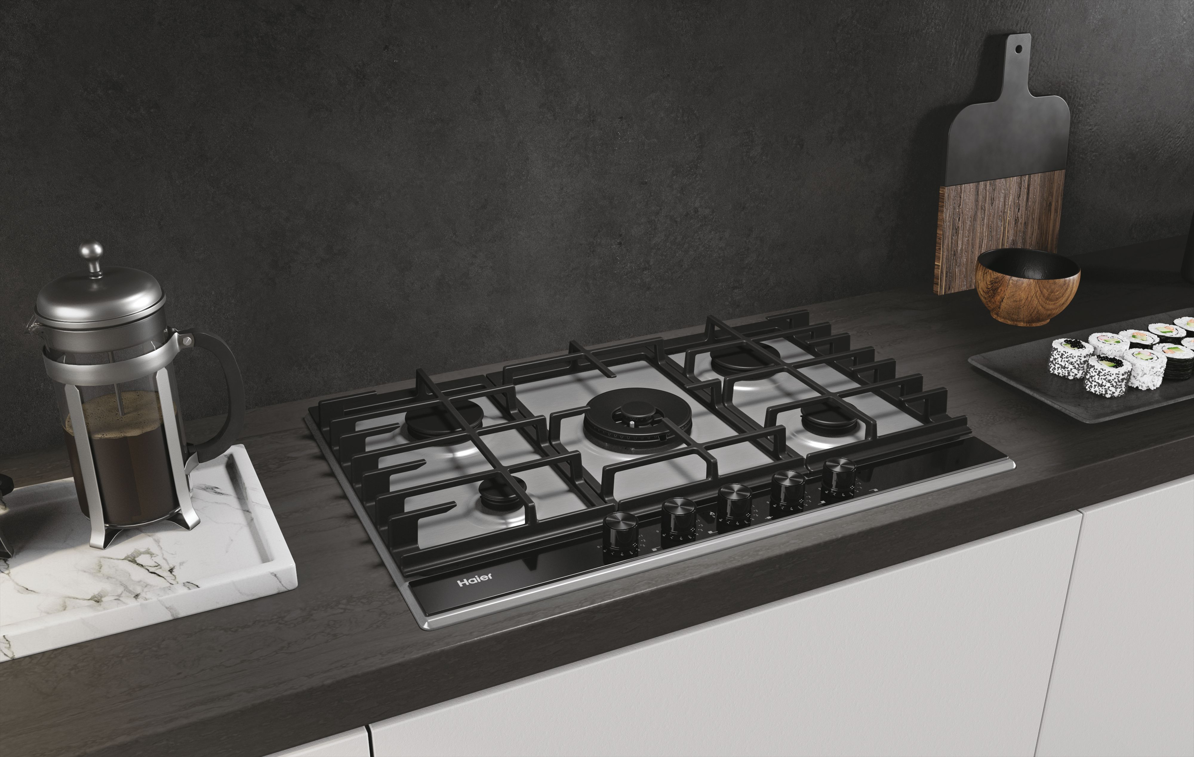 Ustawienie kuchenne ze stalową płytą gazową Haier i różnymi przedmiotami.