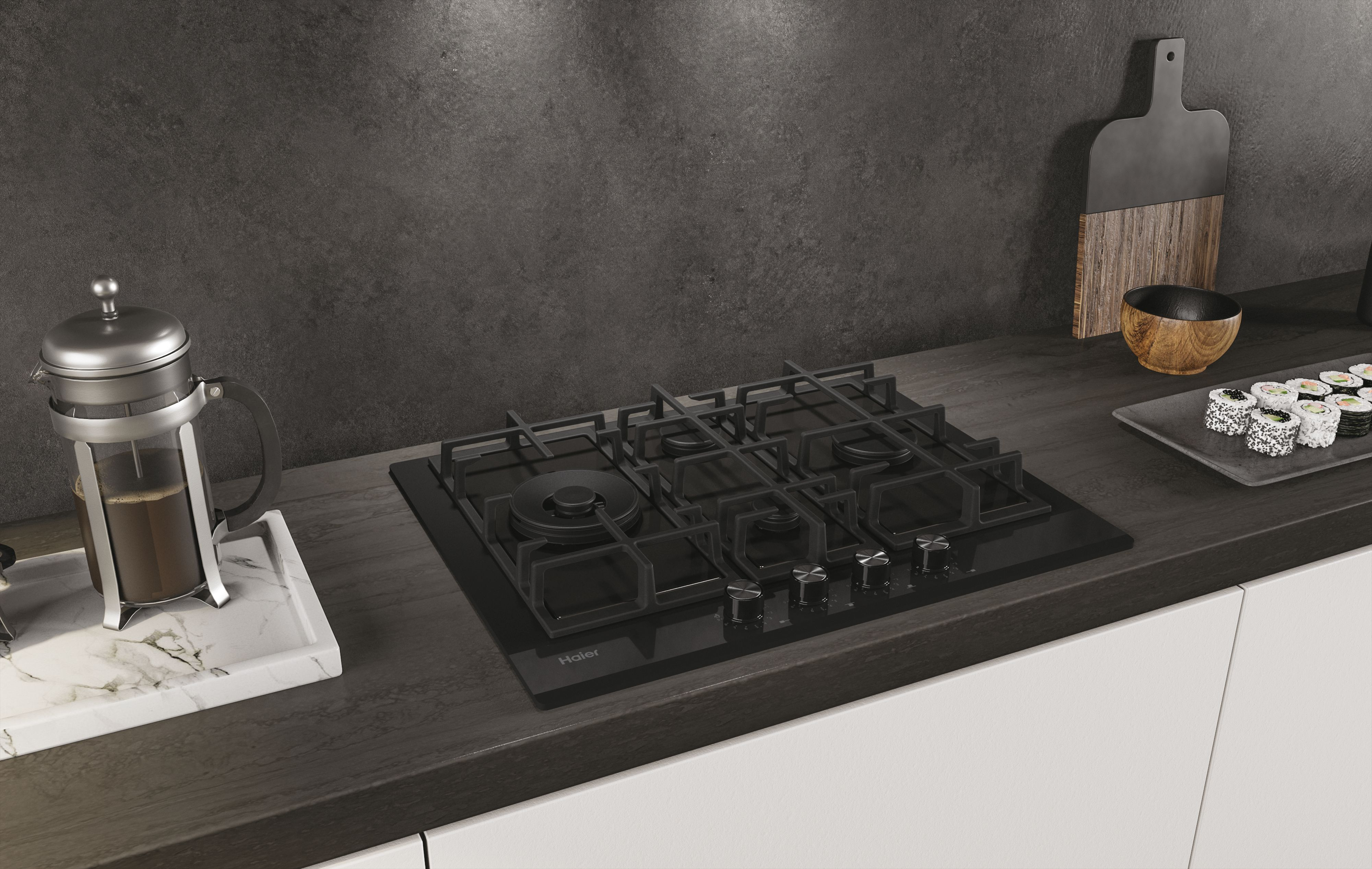 Piano cottura a gas nero installato in un piano cucina. Una caffettiera francese e sushi sul bancone.