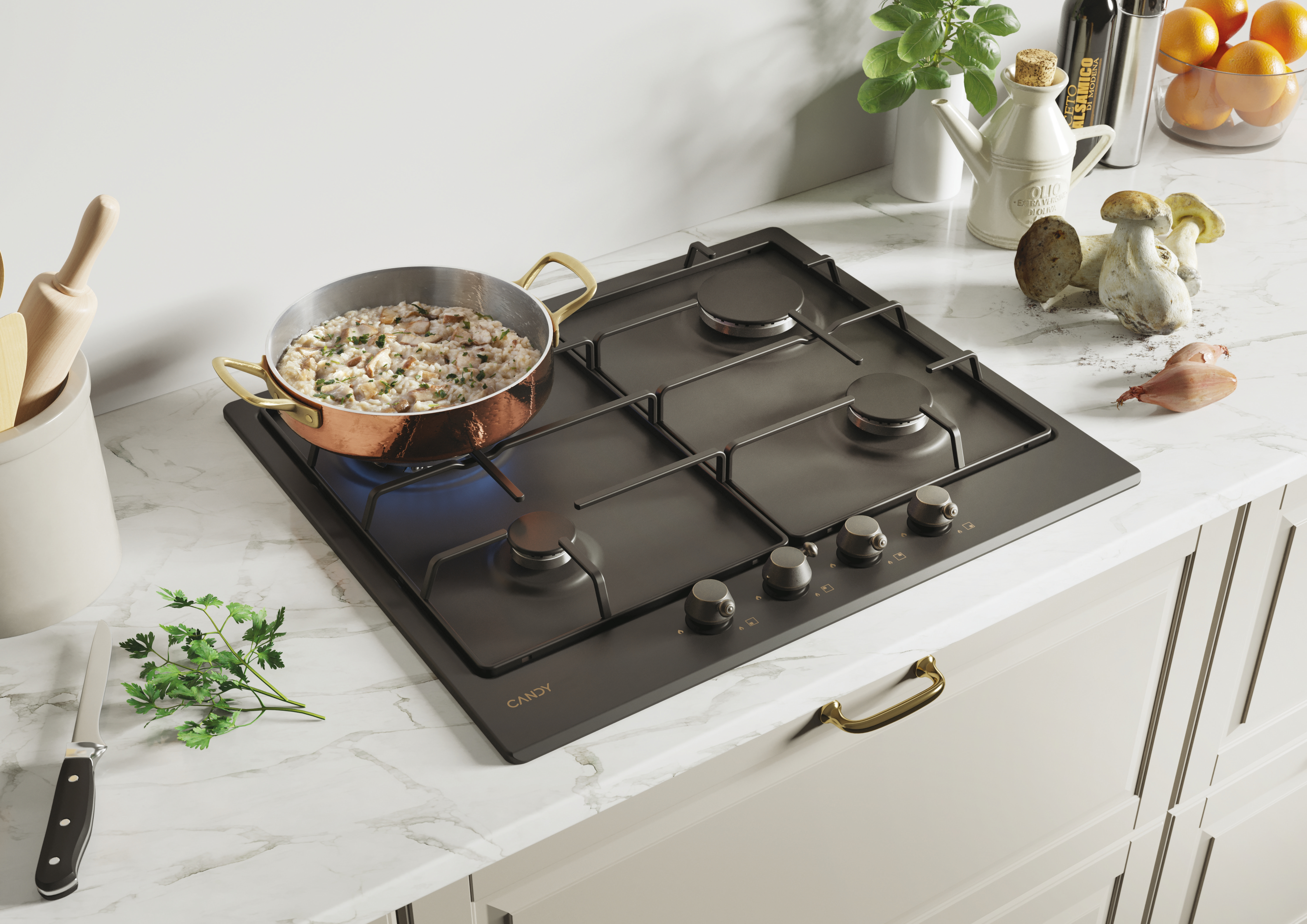 Płyta kuchenna z miedzianą patelnią z gotującym się jedzeniem i innymi przyborami kuchennymi.