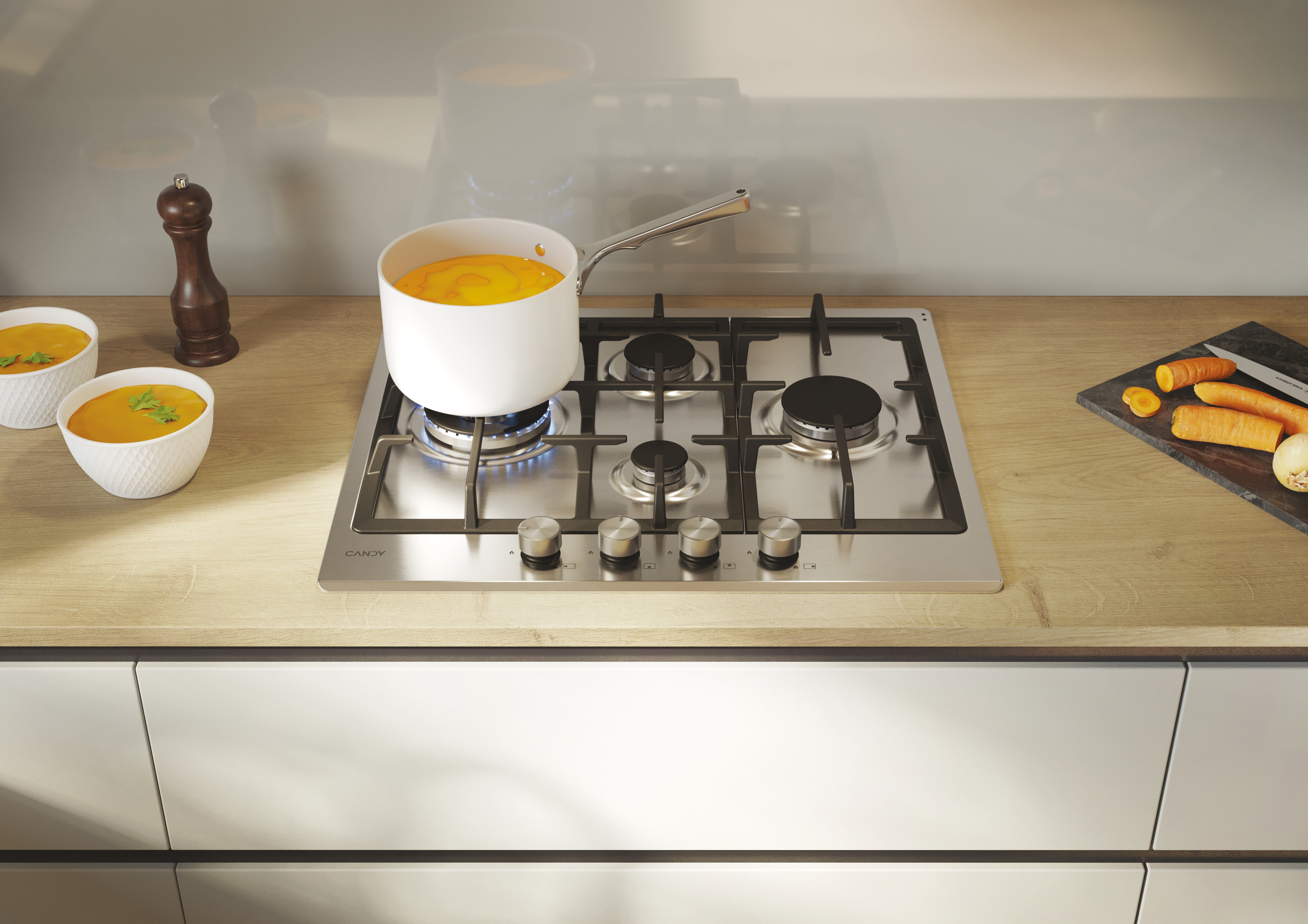 Płyta gazowa ze stali nierdzewnej z garnkiem zupy gotującej się na niej. Marchewki i drewniana łyżka są w pobliżu.