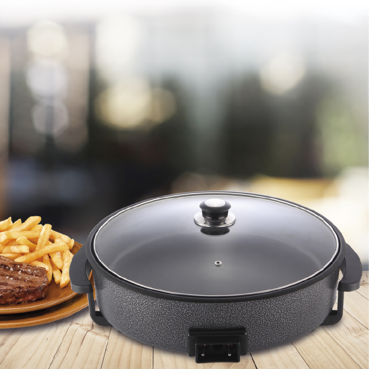 Sartén eléctrico con tapa, bistec y patatas fritas en mesa de madera, fondo borroso.