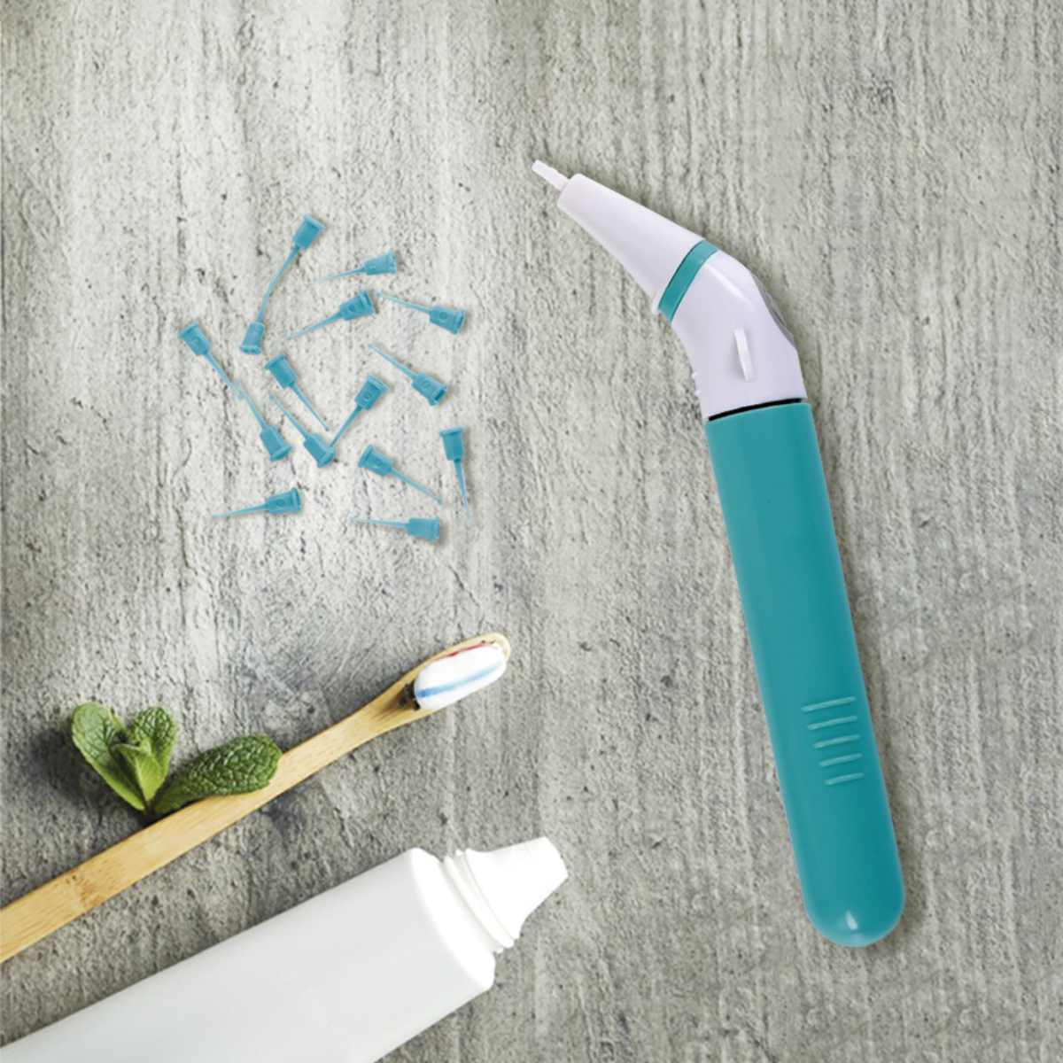 Herramienta de higiene dental con punta azul, pasta de dientes, cepillo y hojas de menta.