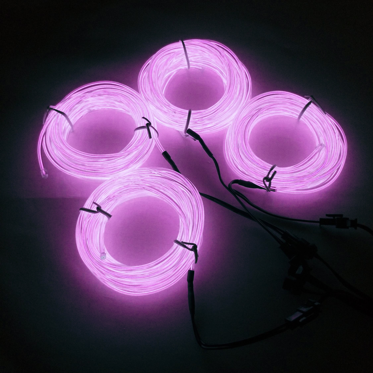 Cuatro cuerdas de luz rosa neón brillante sobre una superficie oscura.