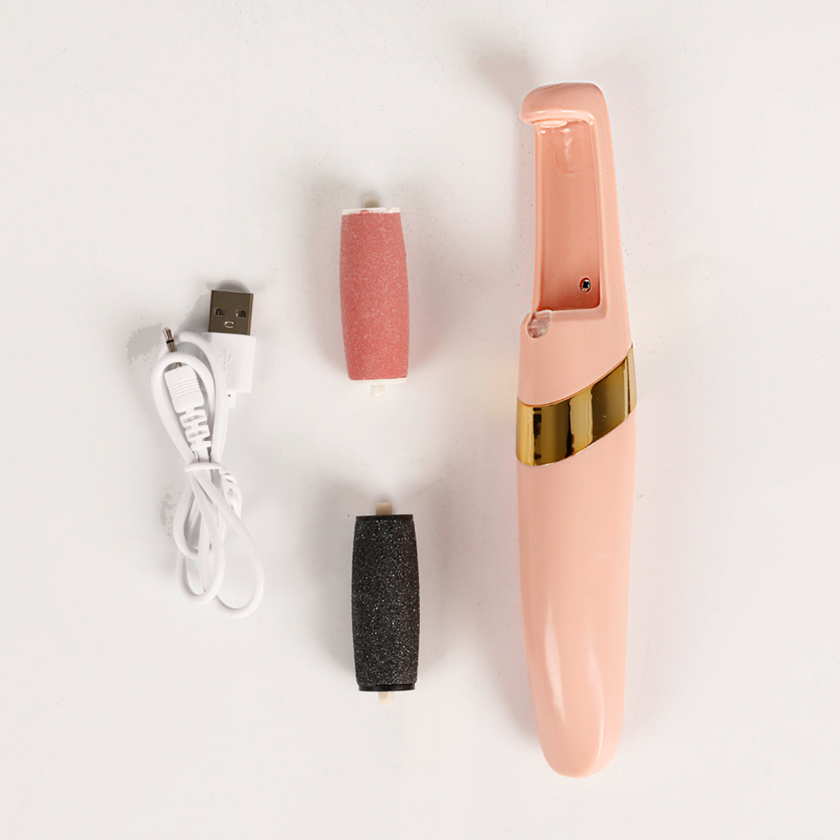 Dispositivo rosa para el cuidado de los pies con dos cabezales de rodillo, un cable de carga y un cabezal extra sobre una superficie blanca.