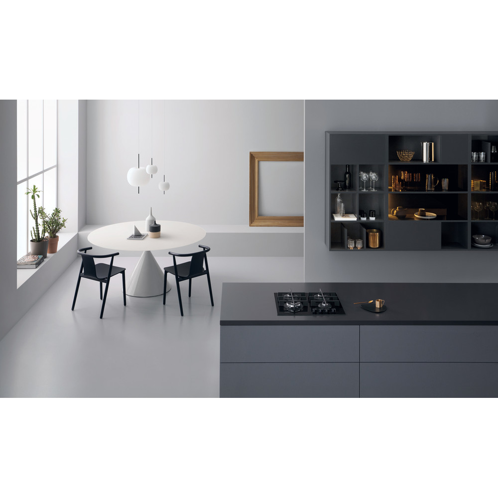 Una cocina moderna con una mesa redonda blanca, sillas negras y una encimera gris oscuro con una placa de cocina.