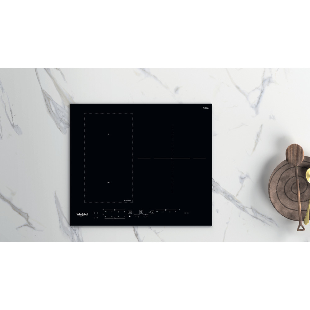 Placa de inducción negra con controles táctiles. Encimera de mármol, objetos de madera.