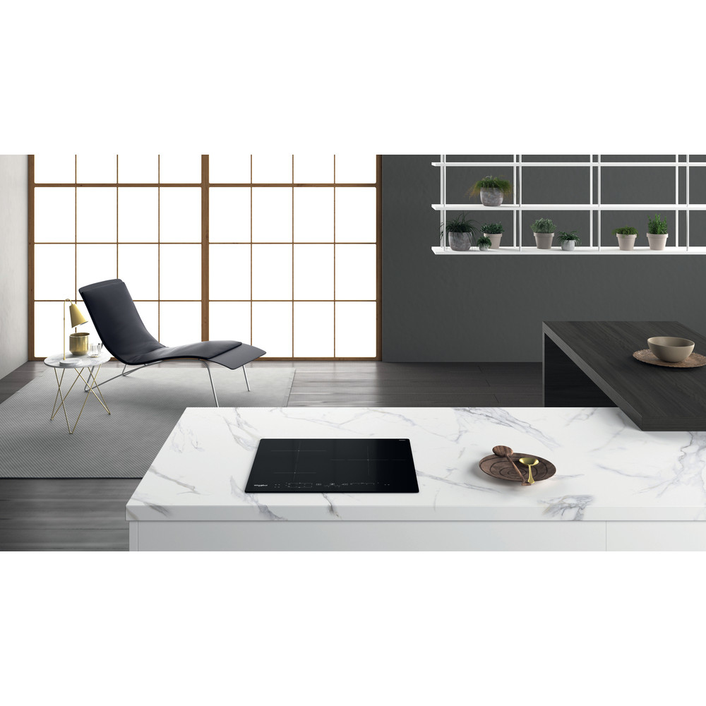 Placa de inducción negra en encimera blanca en un entorno de cocina.
