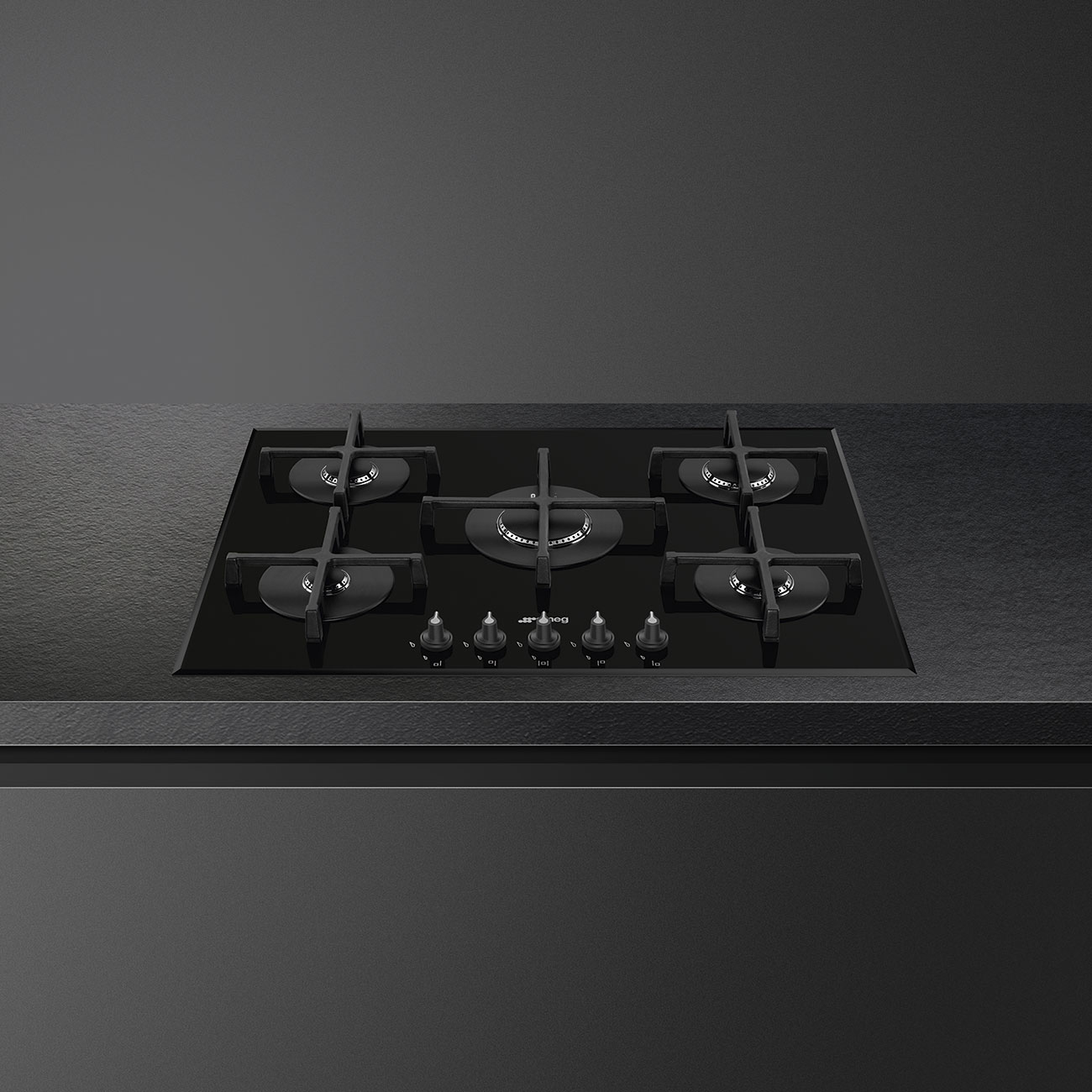 Cocina de gas empotrada negra con cinco quemadores sobre una encimera negra a juego.