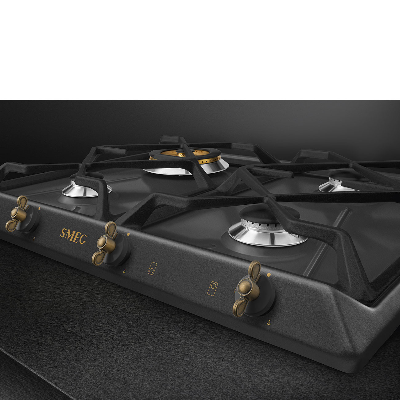 Zbliżenie płyty gazowej z trzema palnikami, złotymi pokrętłami i czarną powierzchnią.