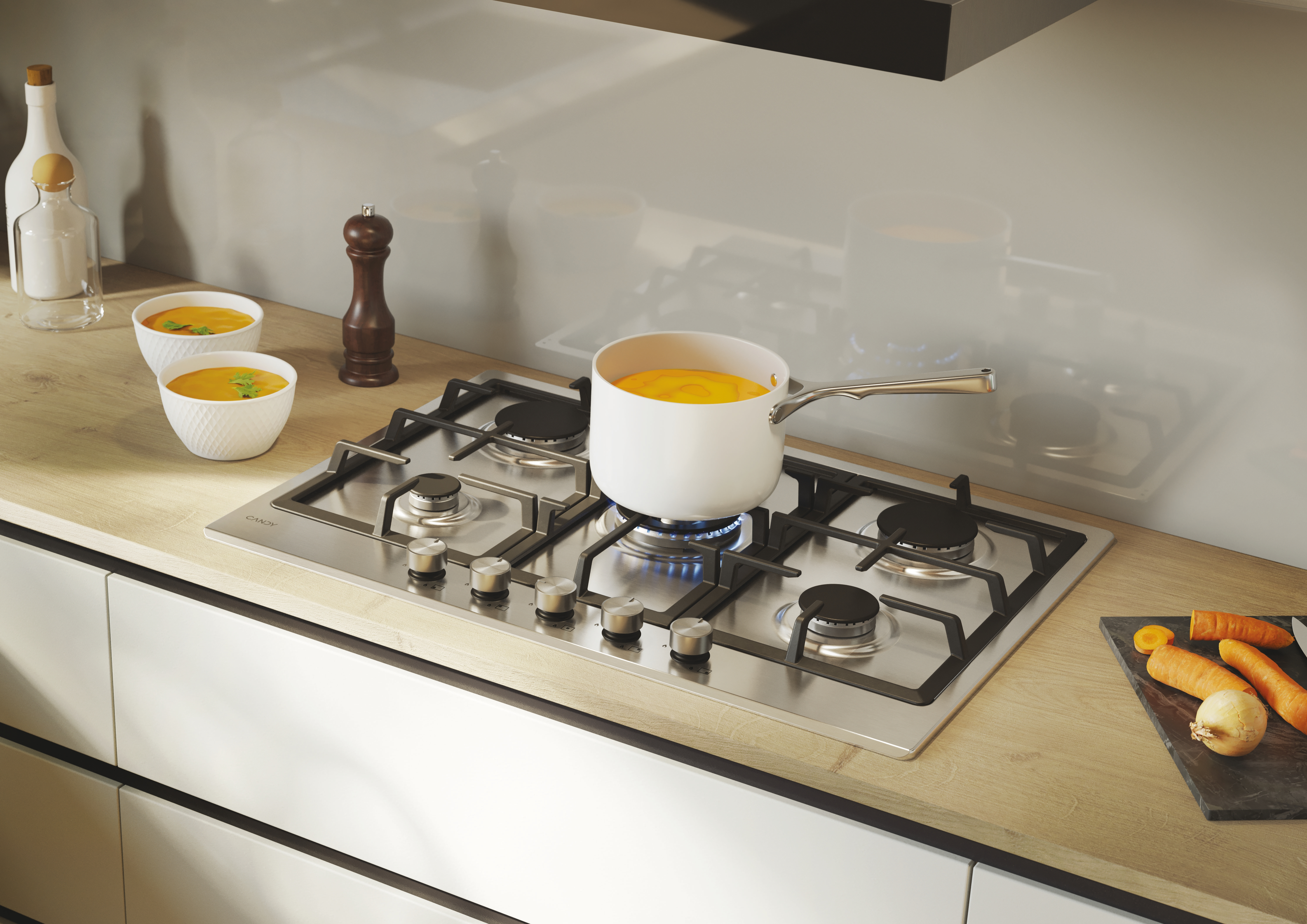 Płyta ze stali nierdzewnej z garnkiem zupy na palniku, marchewką i miskami.