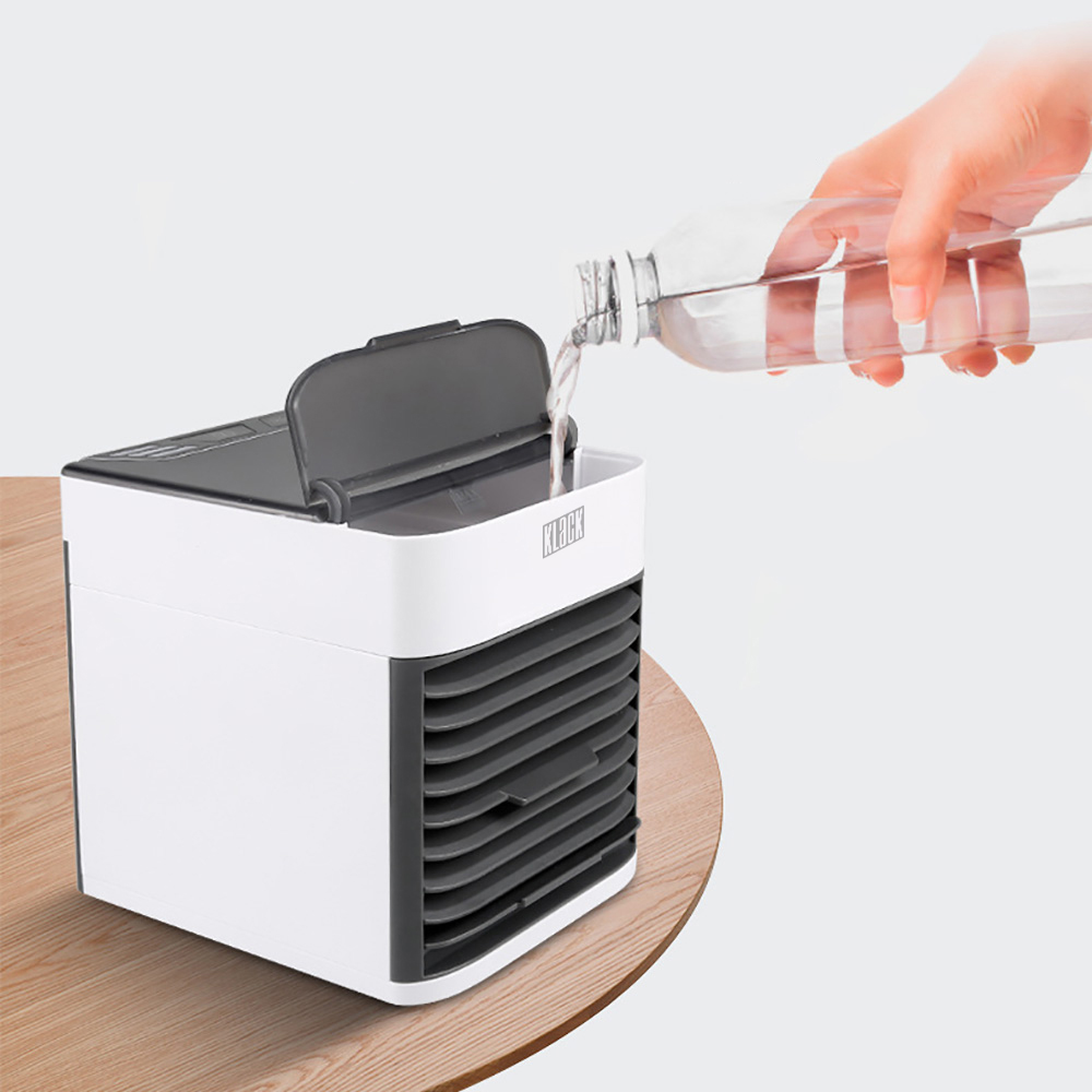 Enfriador de aire, blanco y gris, siendo llenado con agua de una botella transparente. Mesa de madera.