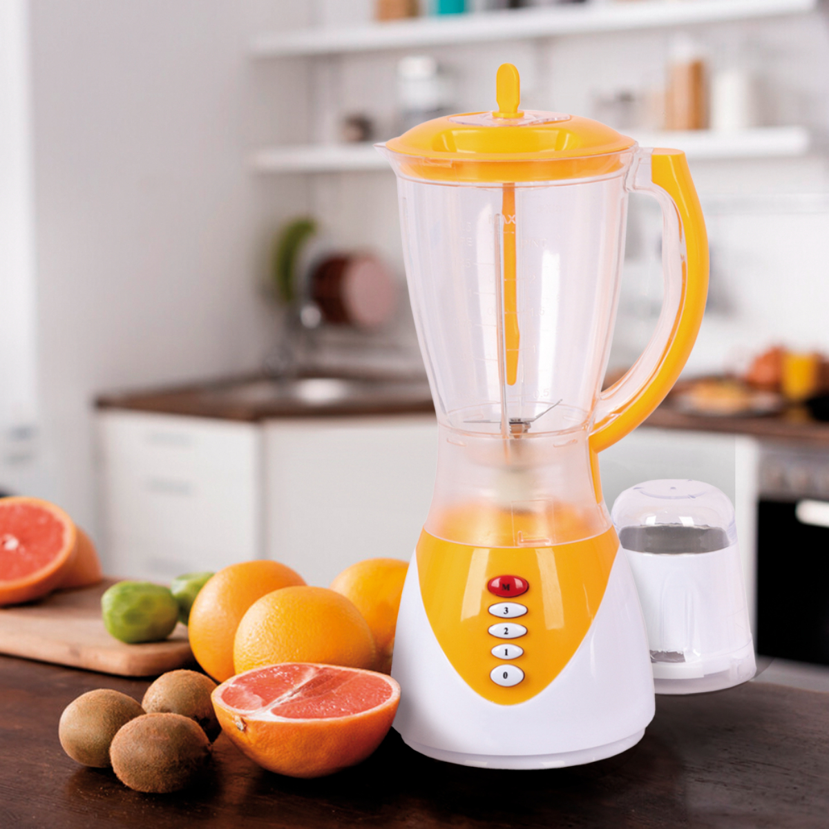 Licuadora amarilla y blanca con frutas: pomelo, naranjas, kiwi y limas sobre una mesa.