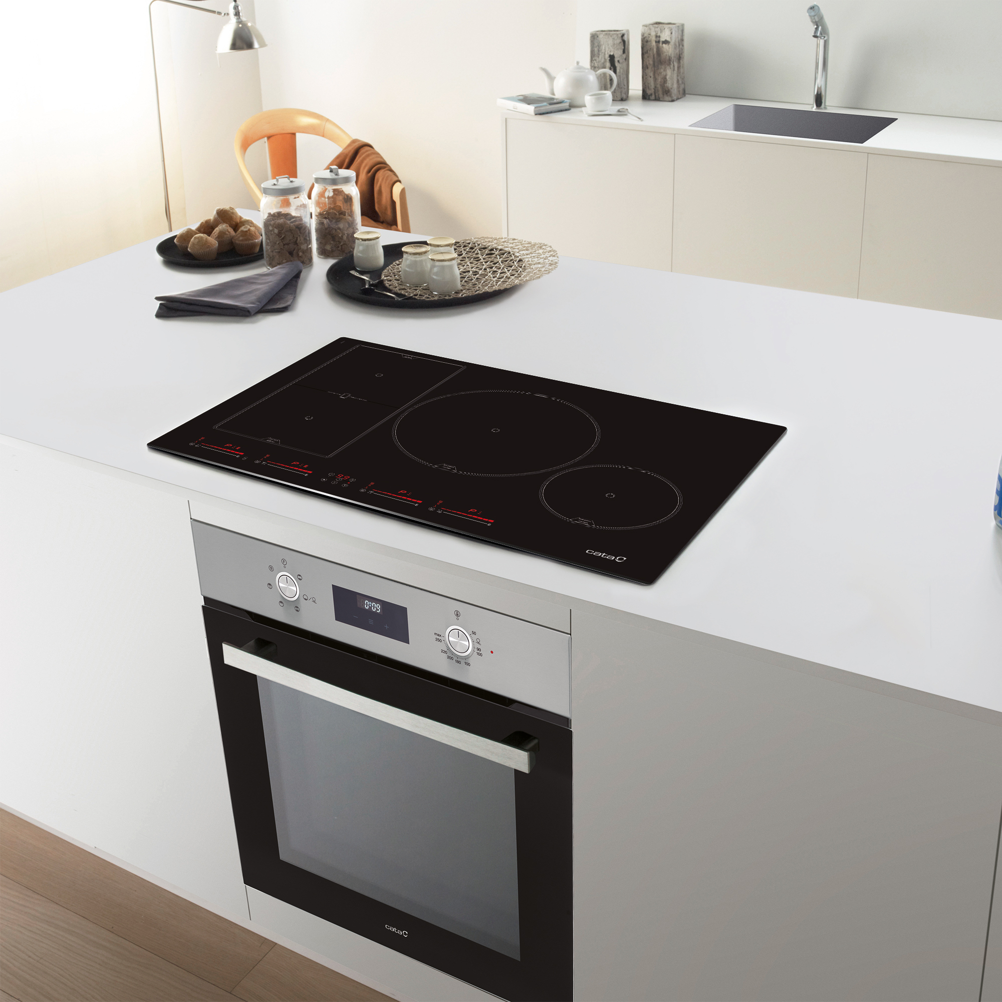 Wnętrze kuchni z czarną płytą indukcyjną Cata na białym blacie. Piekarnik poniżej.