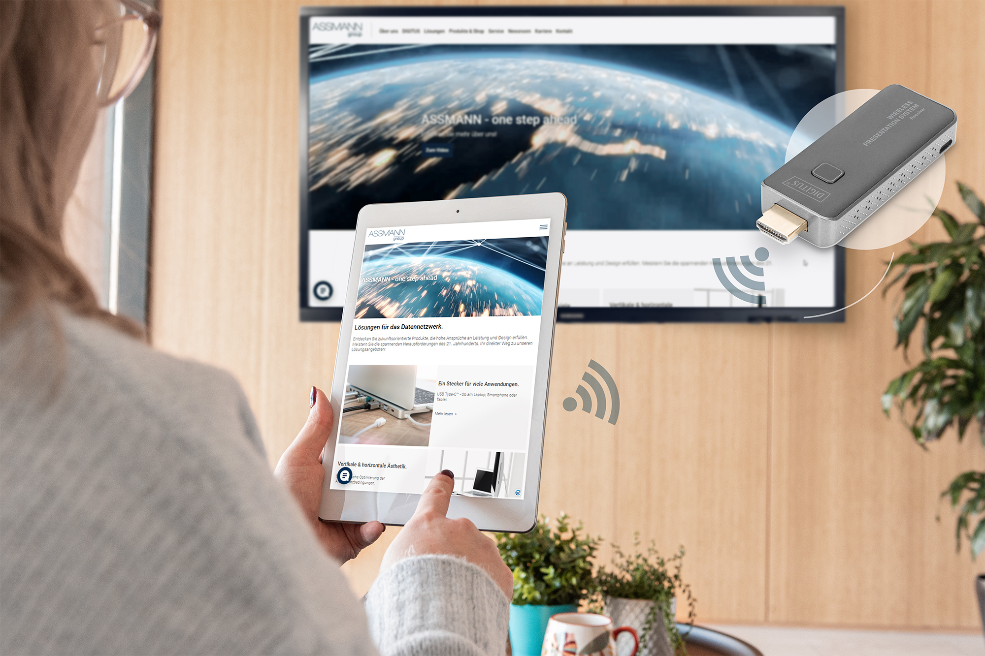 Personne tenant une tablette affichant un site web sur un écran de télévision, connexion sans fil.