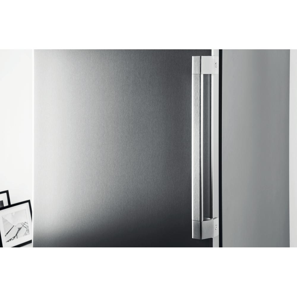 Primer plano de una puerta de refrigerador de acero inoxidable con manija vertical.
